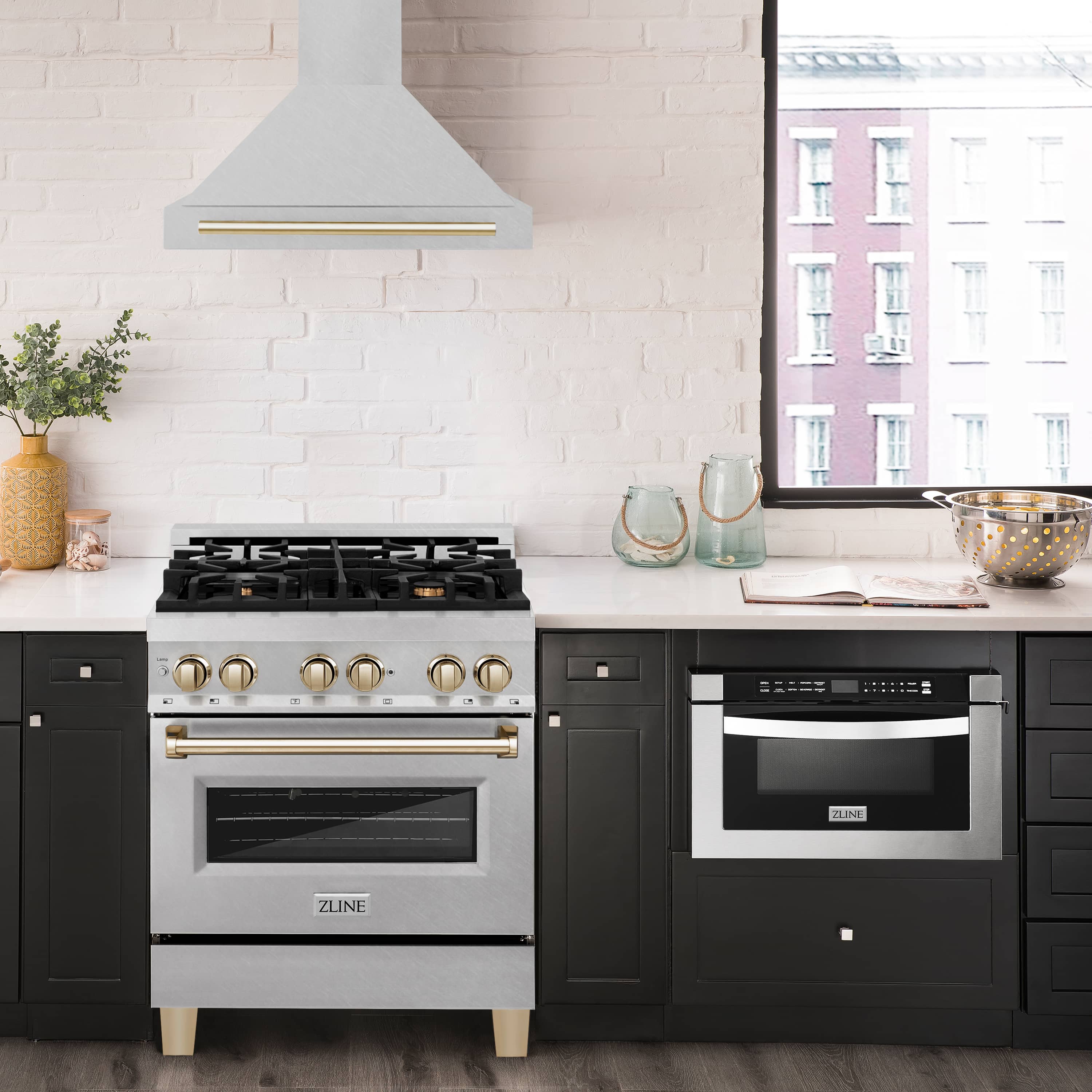 Satin stainless wall-mounted range hood with gold trim above a gas cooktop