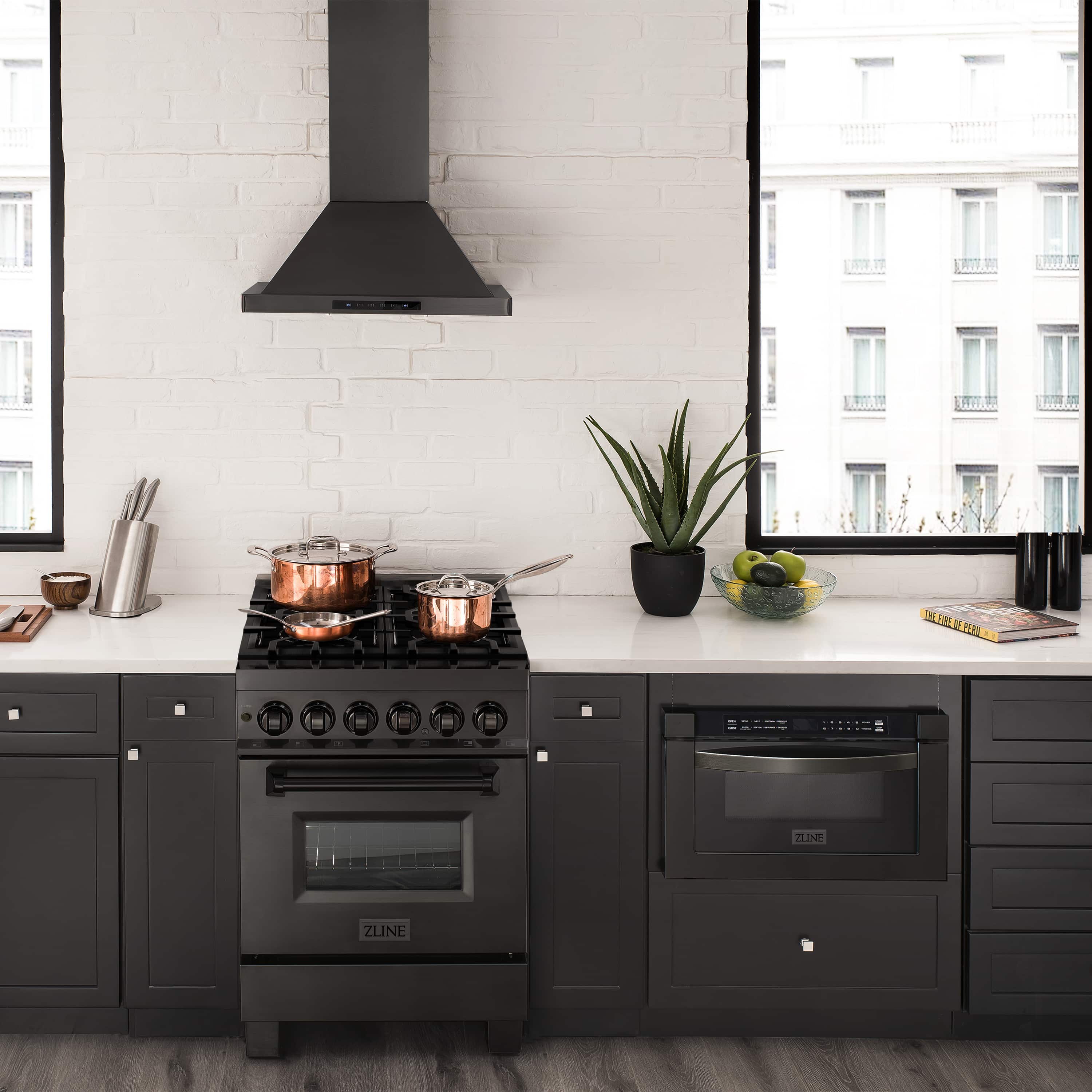 Black stainless dual fuel range with gas burners, oven door, and hood on cabinet kitchen