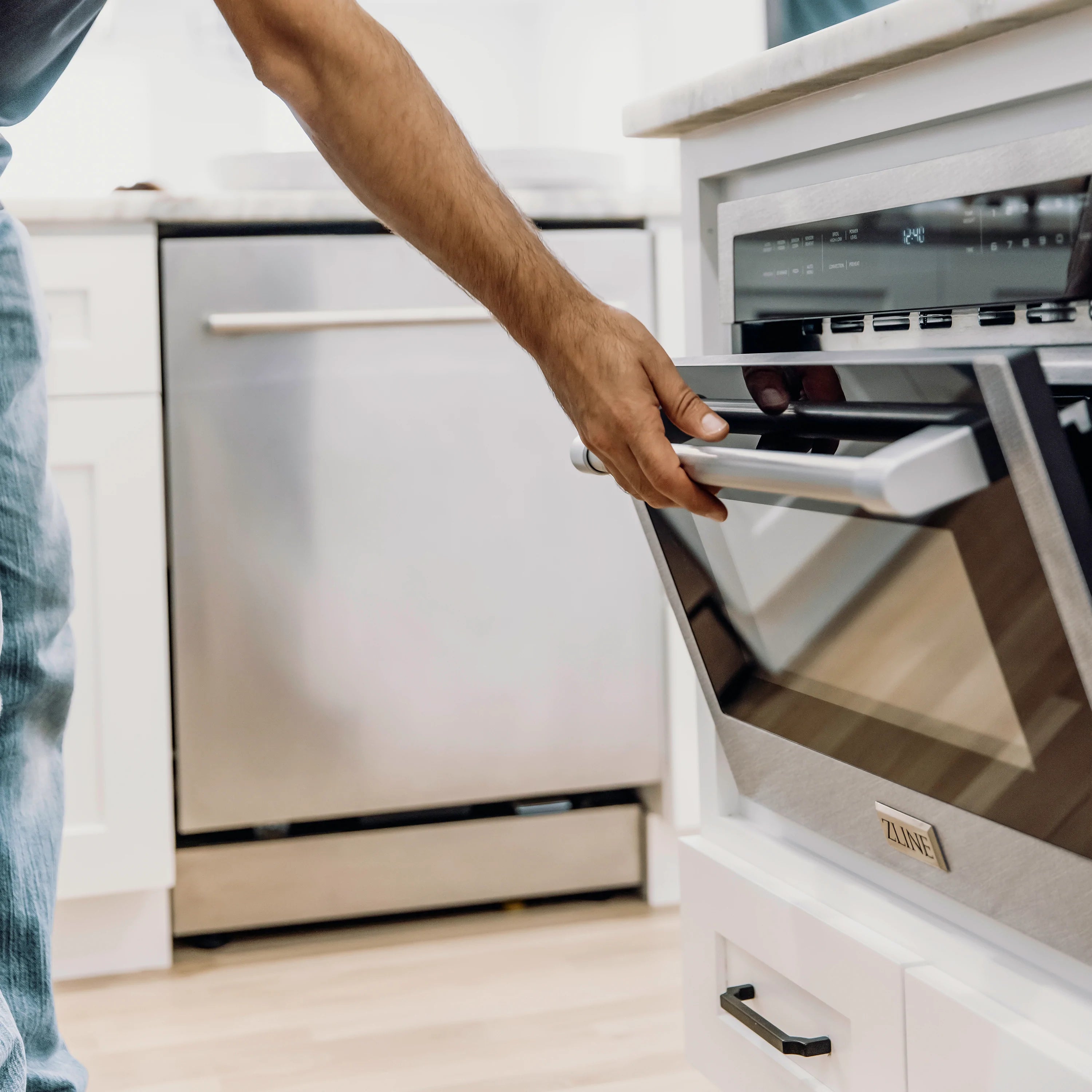 Built-in microwave oven with door open as a person pulls the handle
