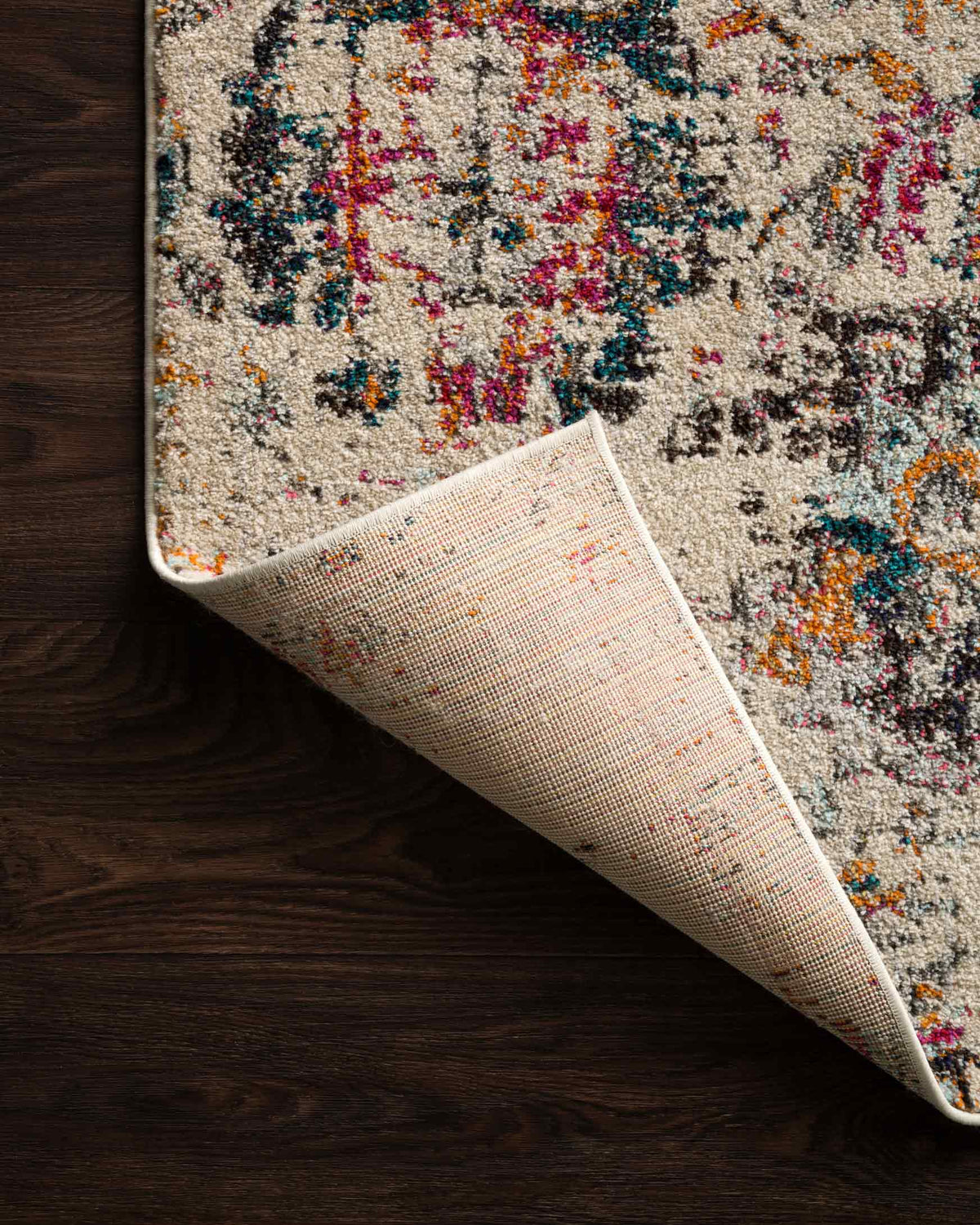 Rolled ivory rug edge with multicolor distressed design and woven backing grid visible