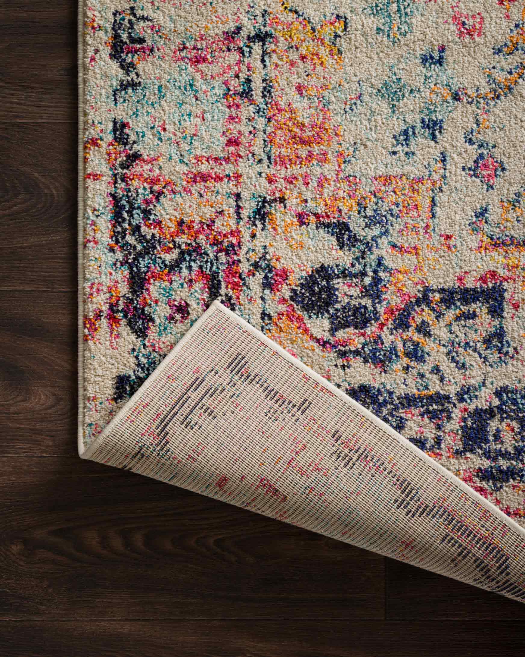 Ivory multicolor rug edge with selvedge visible, patterned surface on wood floor