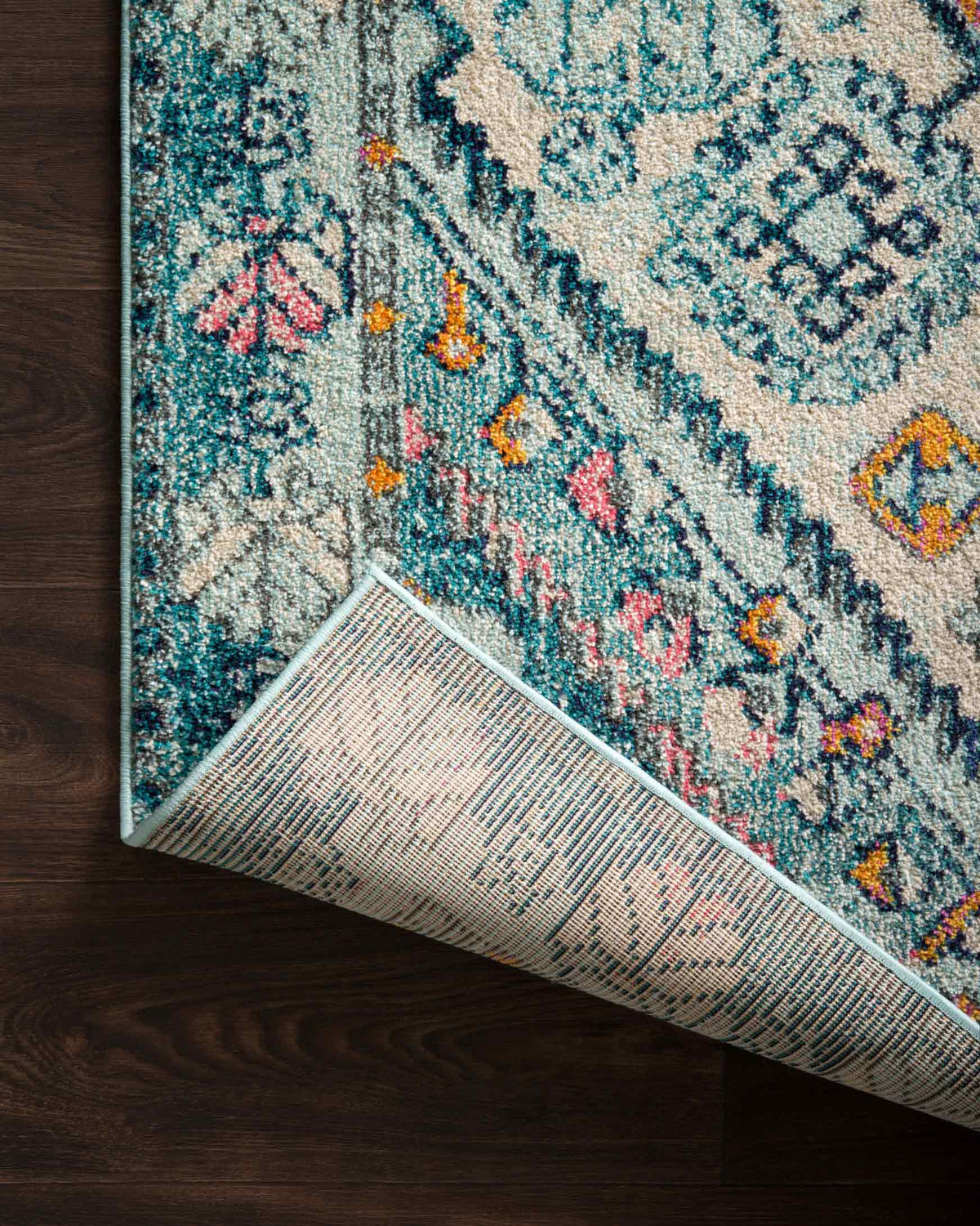 Aqua and navy rug edge showing textured weave and geometric pattern on binding