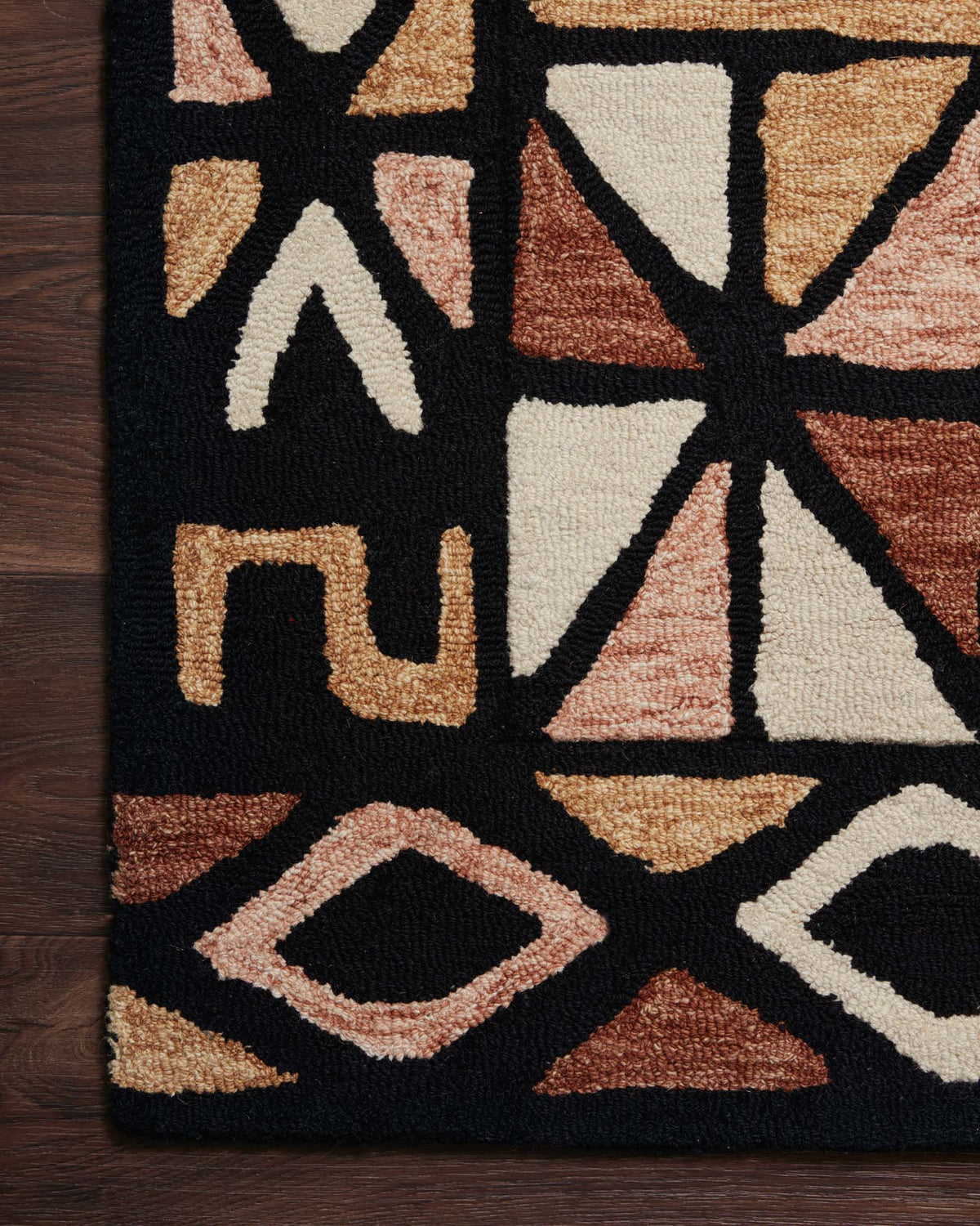 Close-up of hand-tufted rug showing geometric shapes in black, cream, and spice brown.