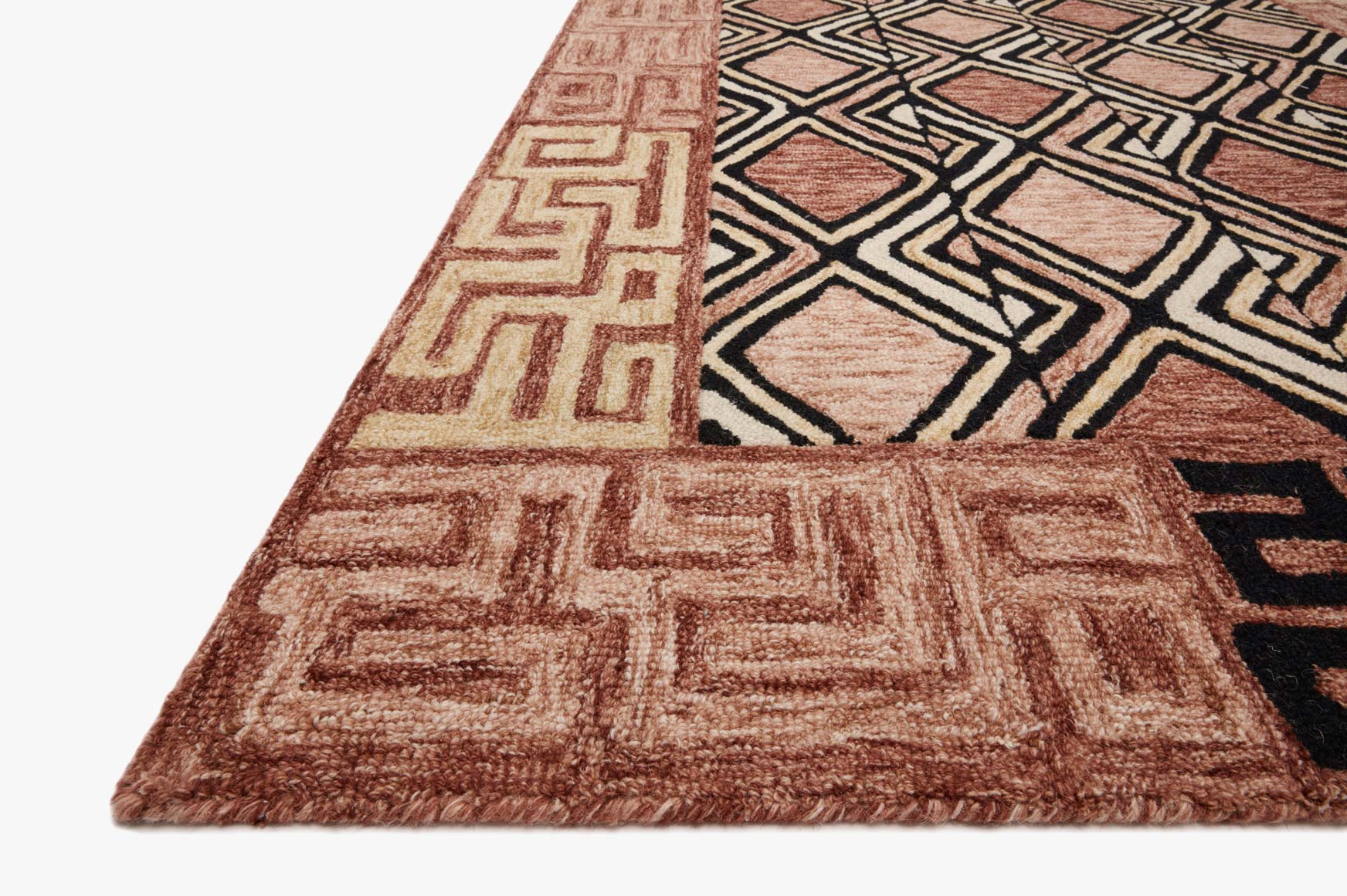 Corner view of rose and black geometric rug with Greek-key border and diamond motifs.