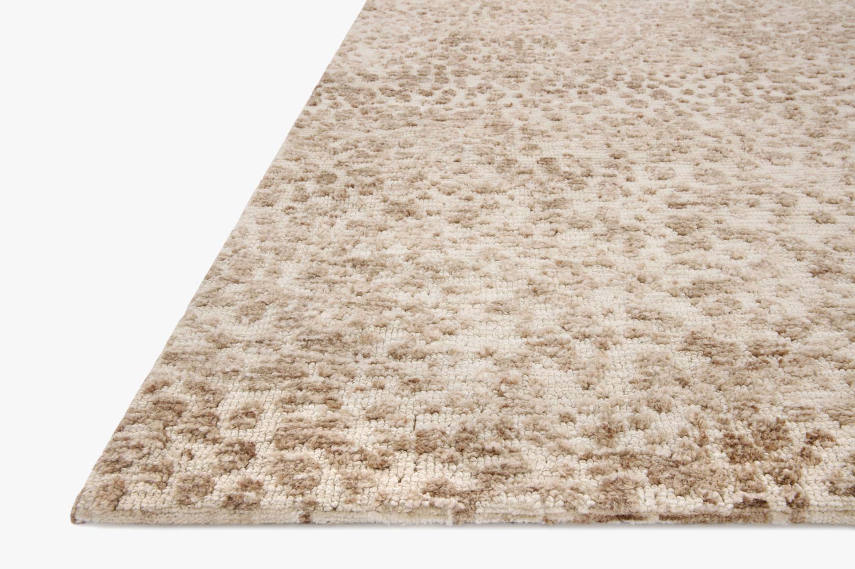 Ivory and sand rug with dense speckled texture and short pile, angled corner