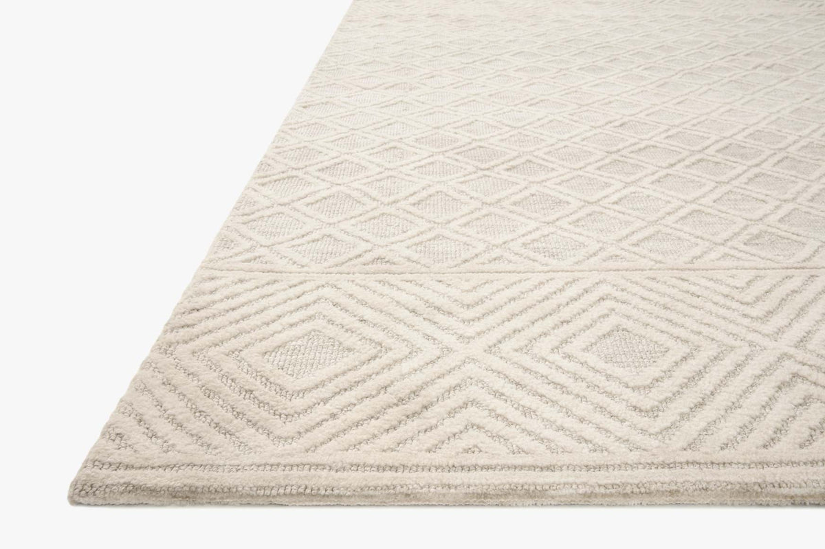 Corner view of ivory and natural power loomed rug with repeating chevron pattern