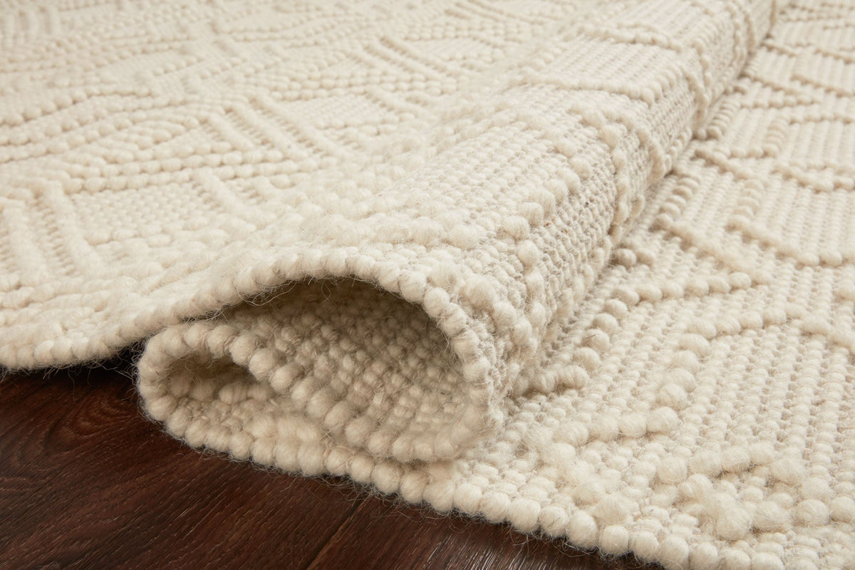 Ivory rug close-up with thick woven texture and curved edge detail