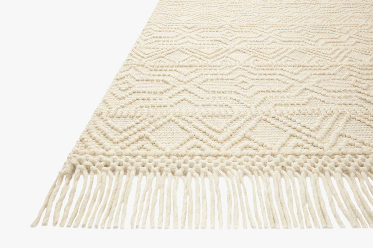 Ivory rug corner with woven diamond pattern and short fringe border