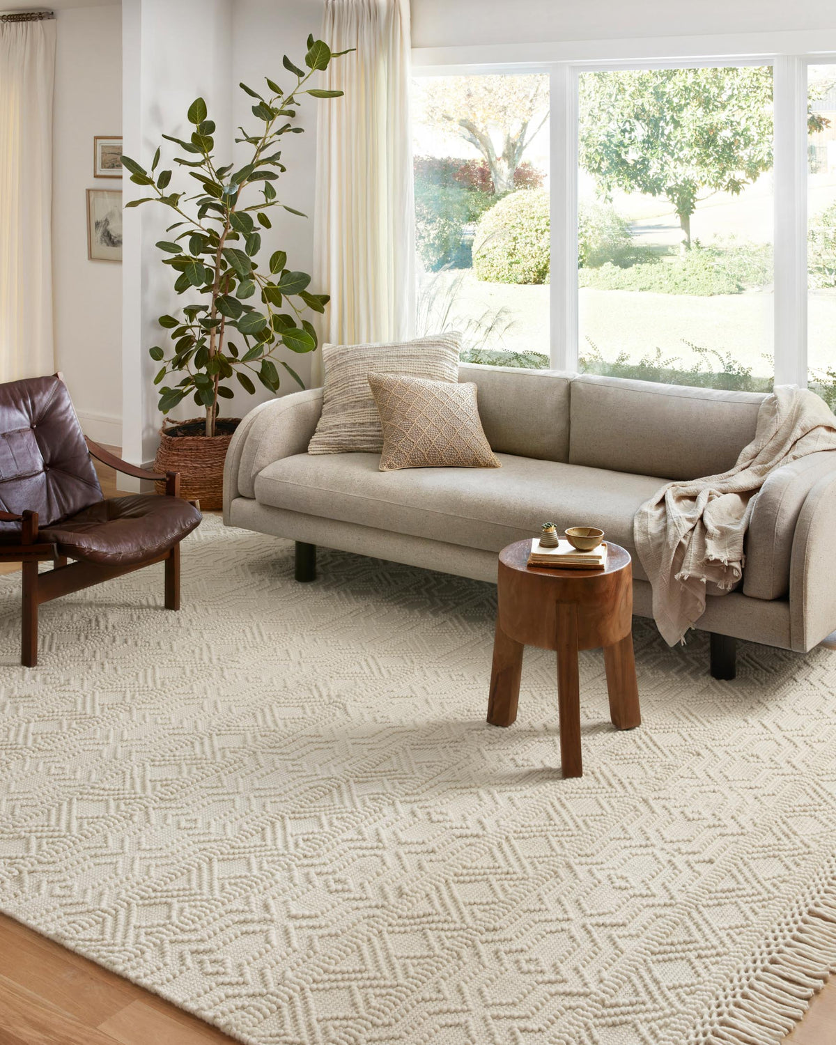 Ivory geometric hand-woven area rug with short fringe, shown under seating