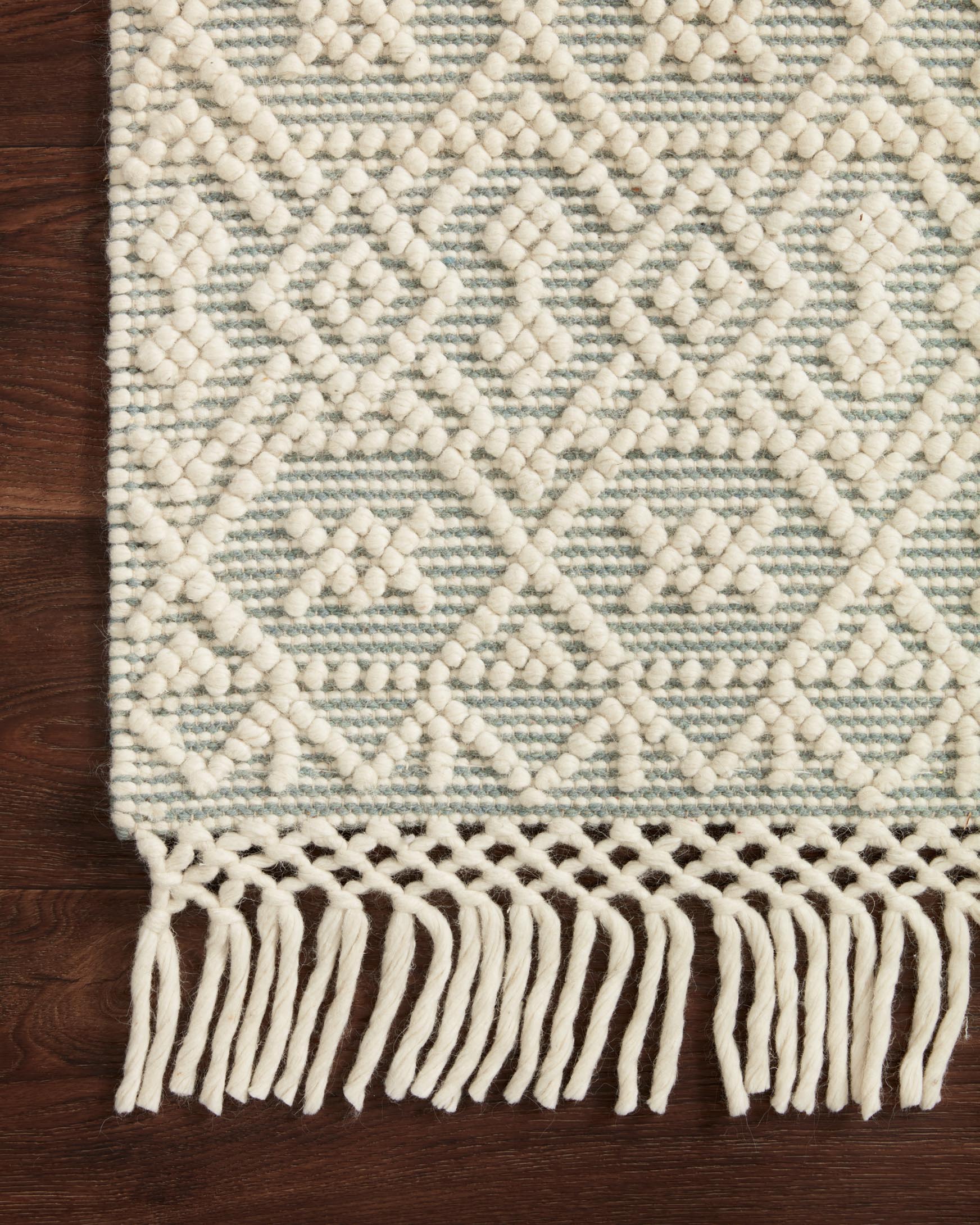 Ivory and blue diamond motif rug with short tassel fringe on the border