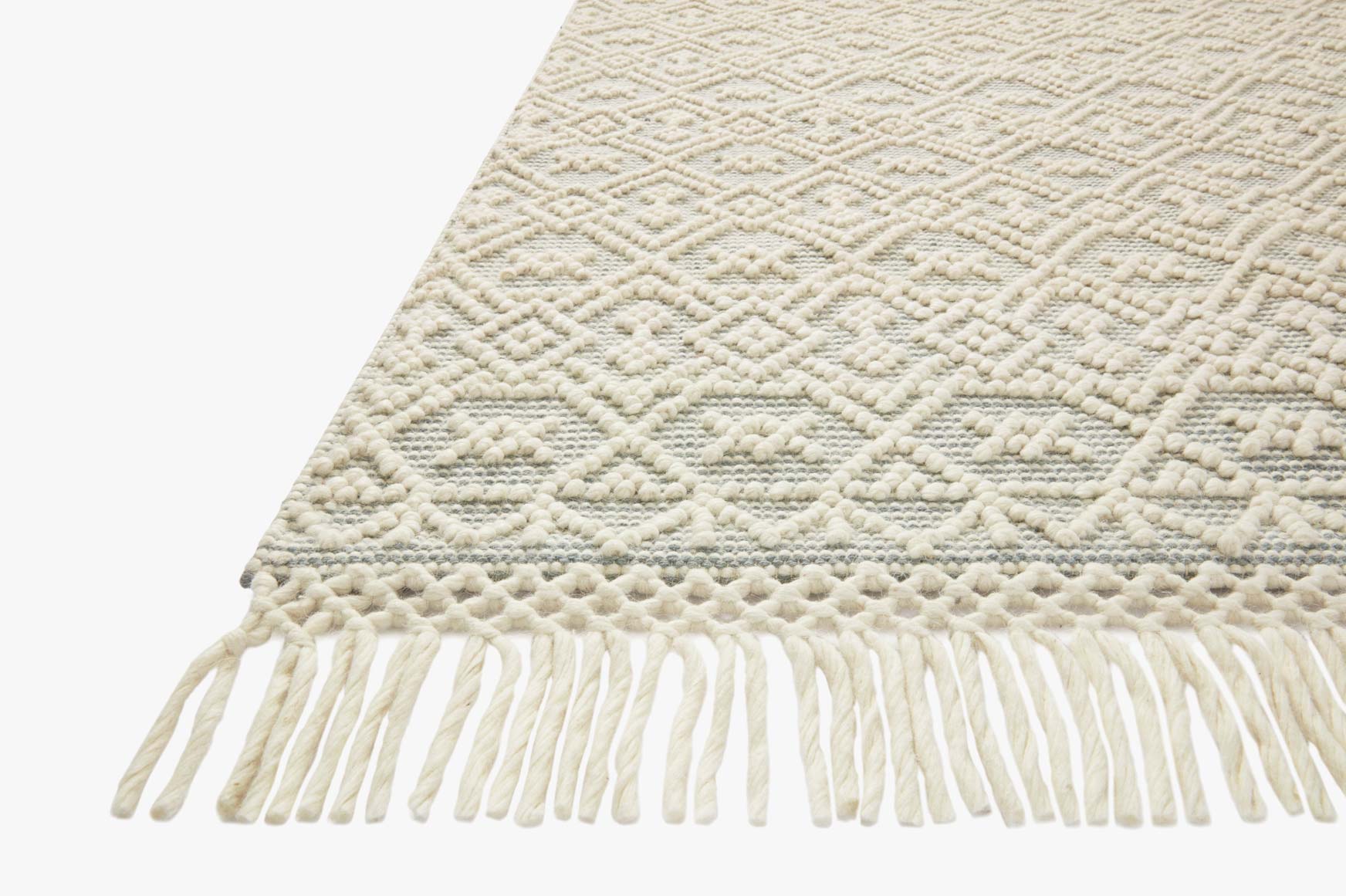 Ivory handwoven rug corner with diamond texture and long white fringe tassels