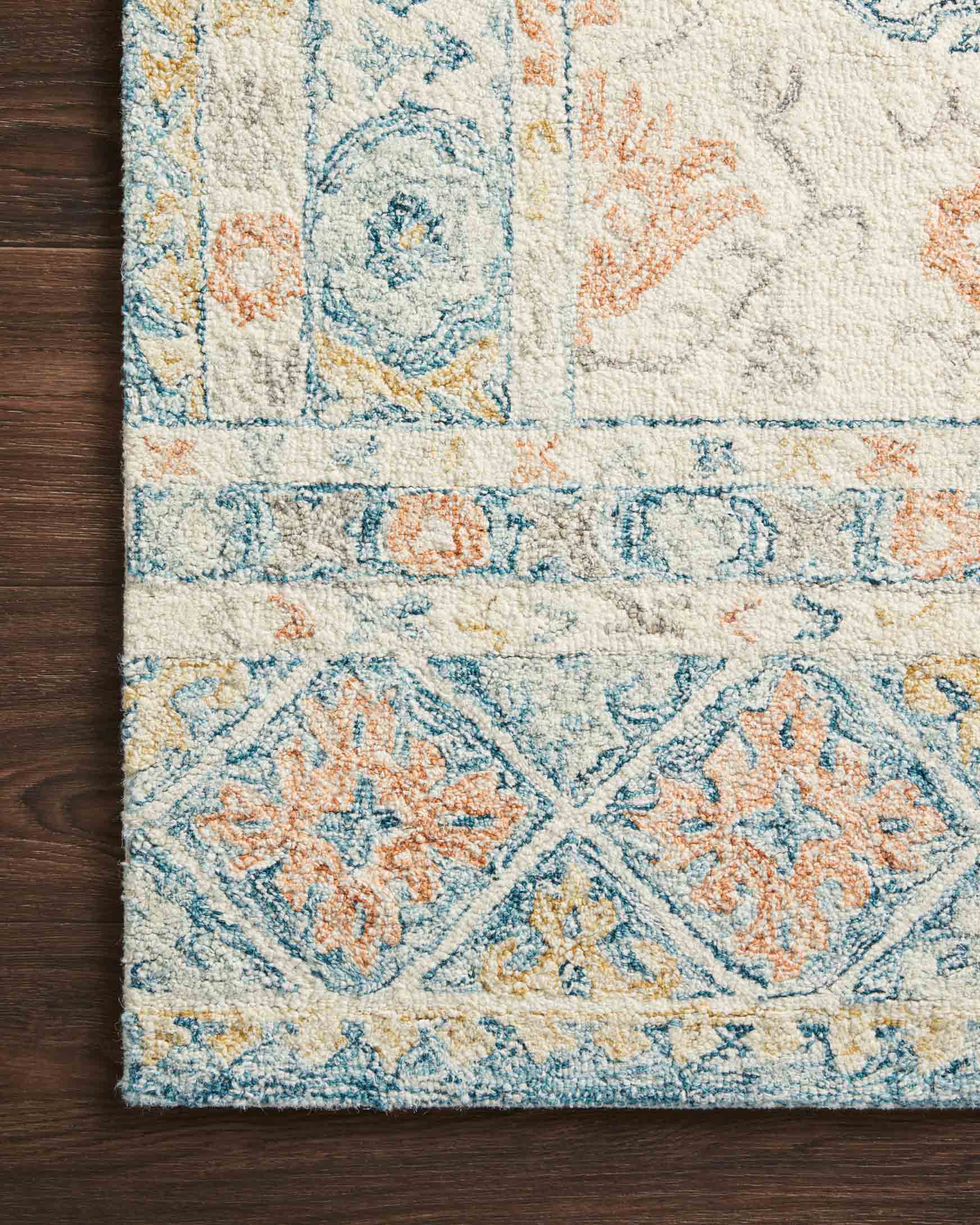 Close-up of ivory hooked rug pile with blue and orange floral medallion pattern