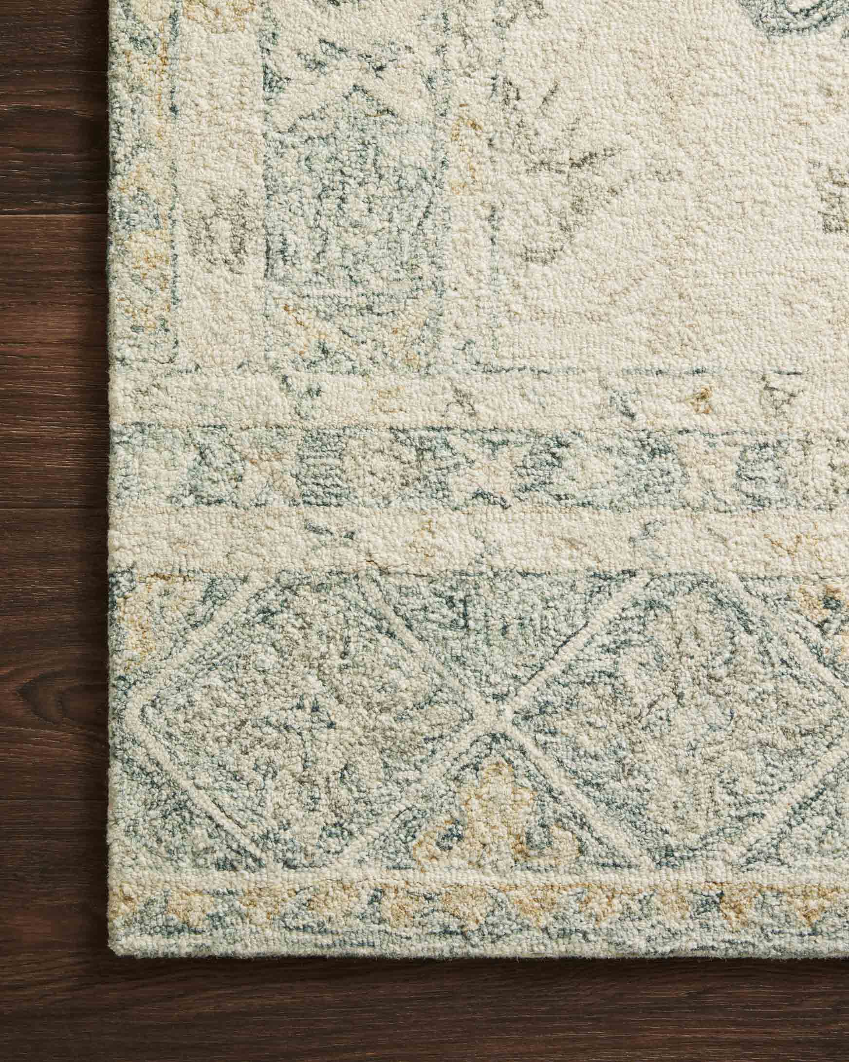 Hooked rug close-up with distressed motif texture in ivory and slate tones
