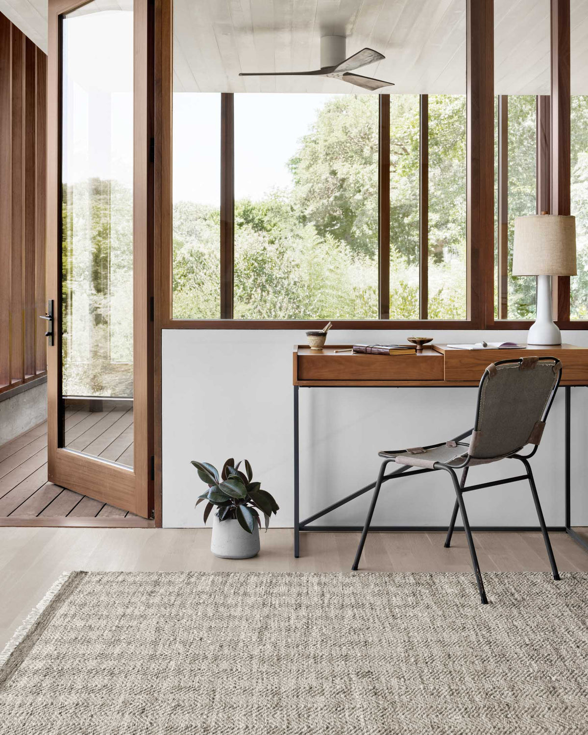 Grey woven area rug with tight border, placed flat on the floor in a room.