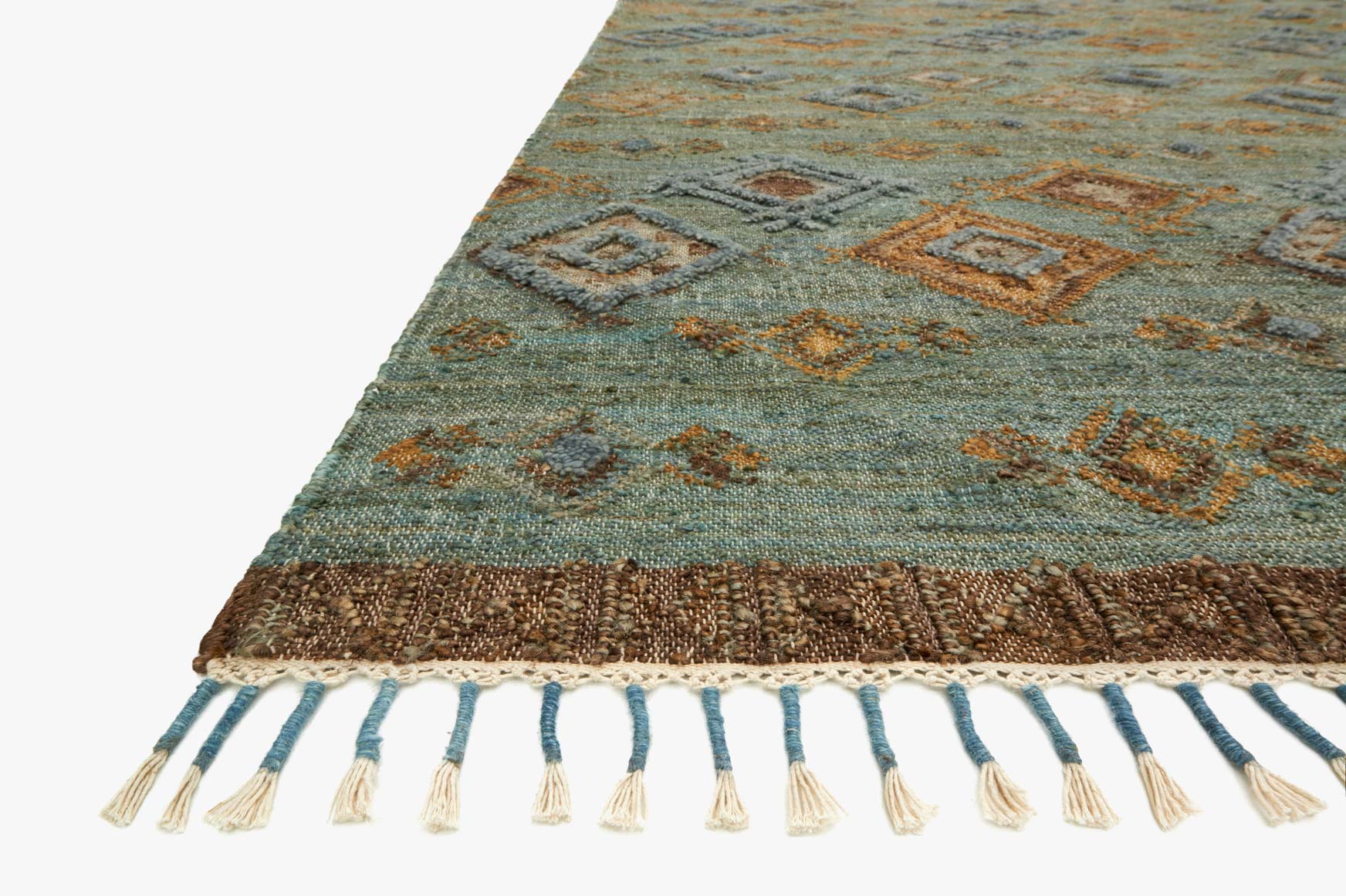 Hand-woven rug corner detail, sea-green blue with diamond motif and tasseled fringe