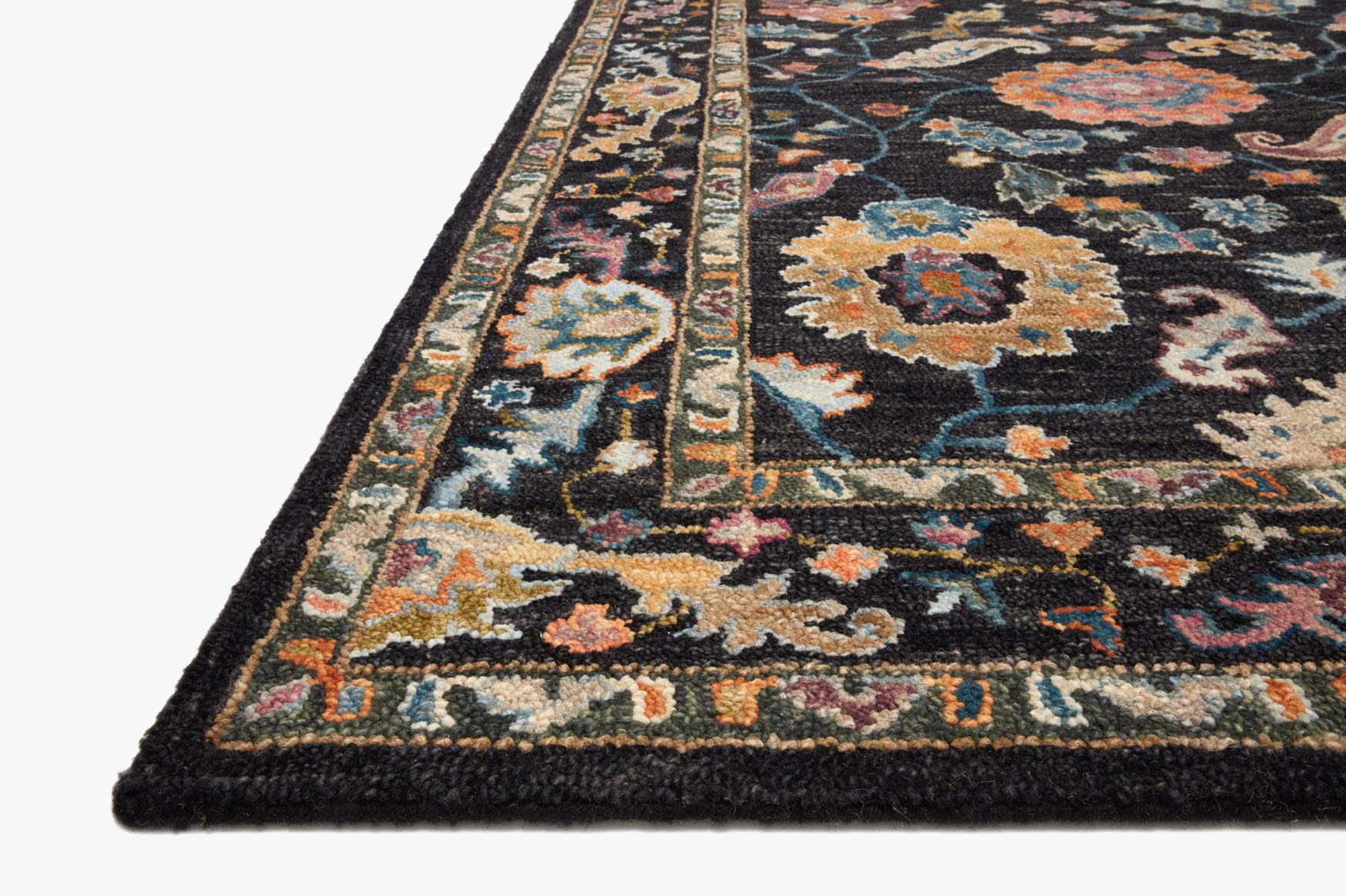 Corner of black hooked rug with multicolor pattern and dark bound edge