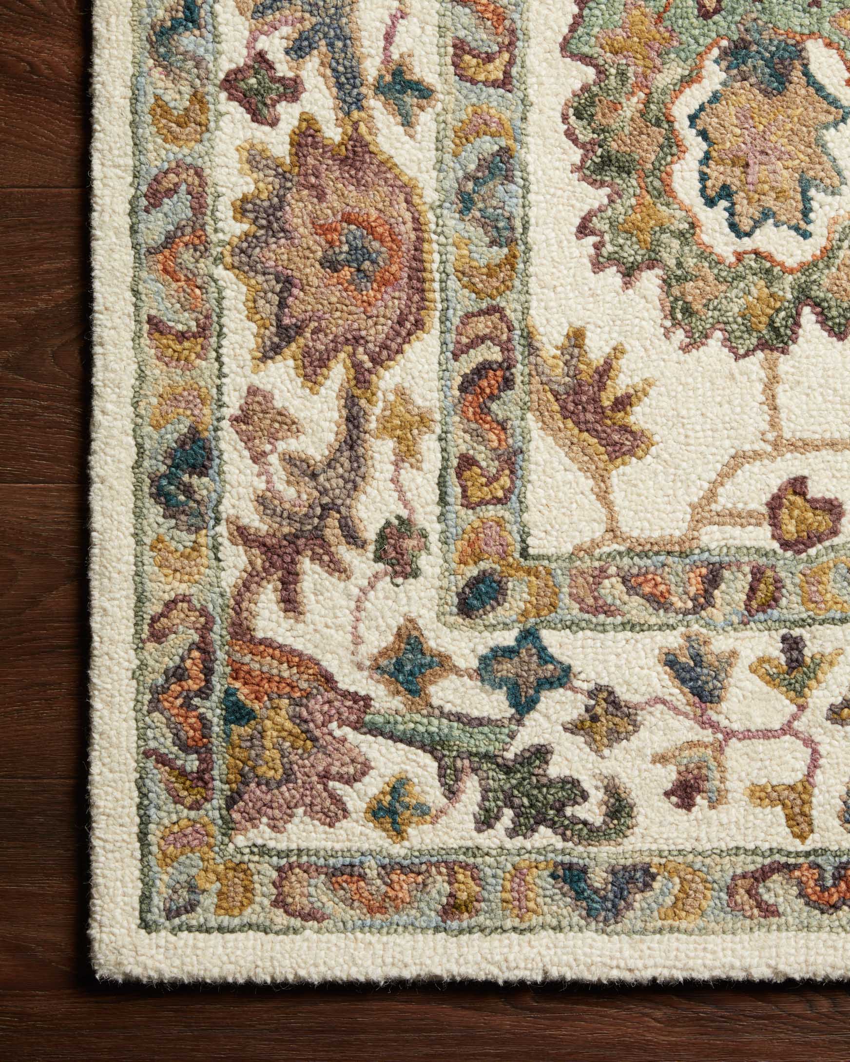 Transitional hooked rug close-up showing hooked texture and multicolor floral motif on white