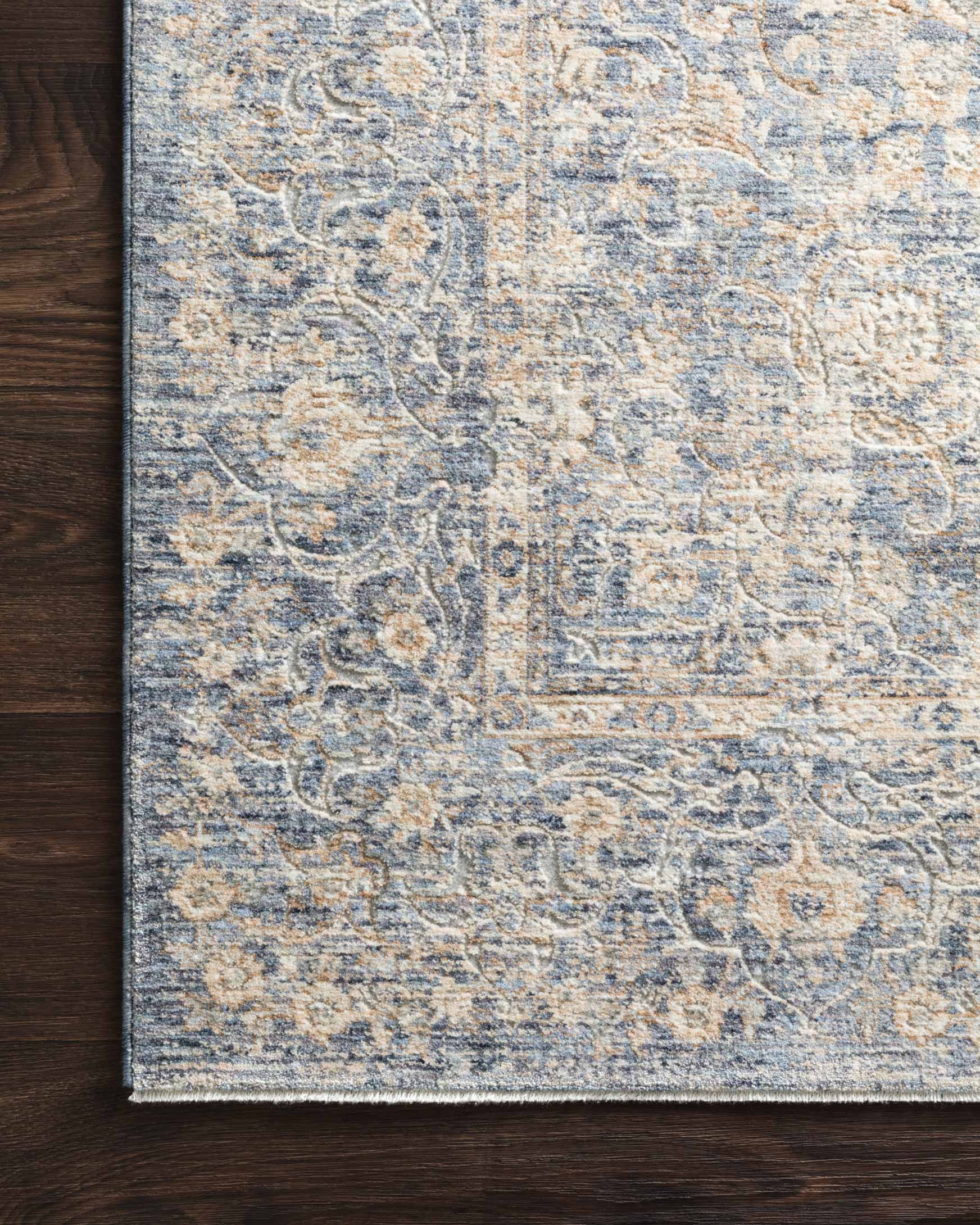 Rug close-up showing light blue field and gold-toned ornamental linework border
