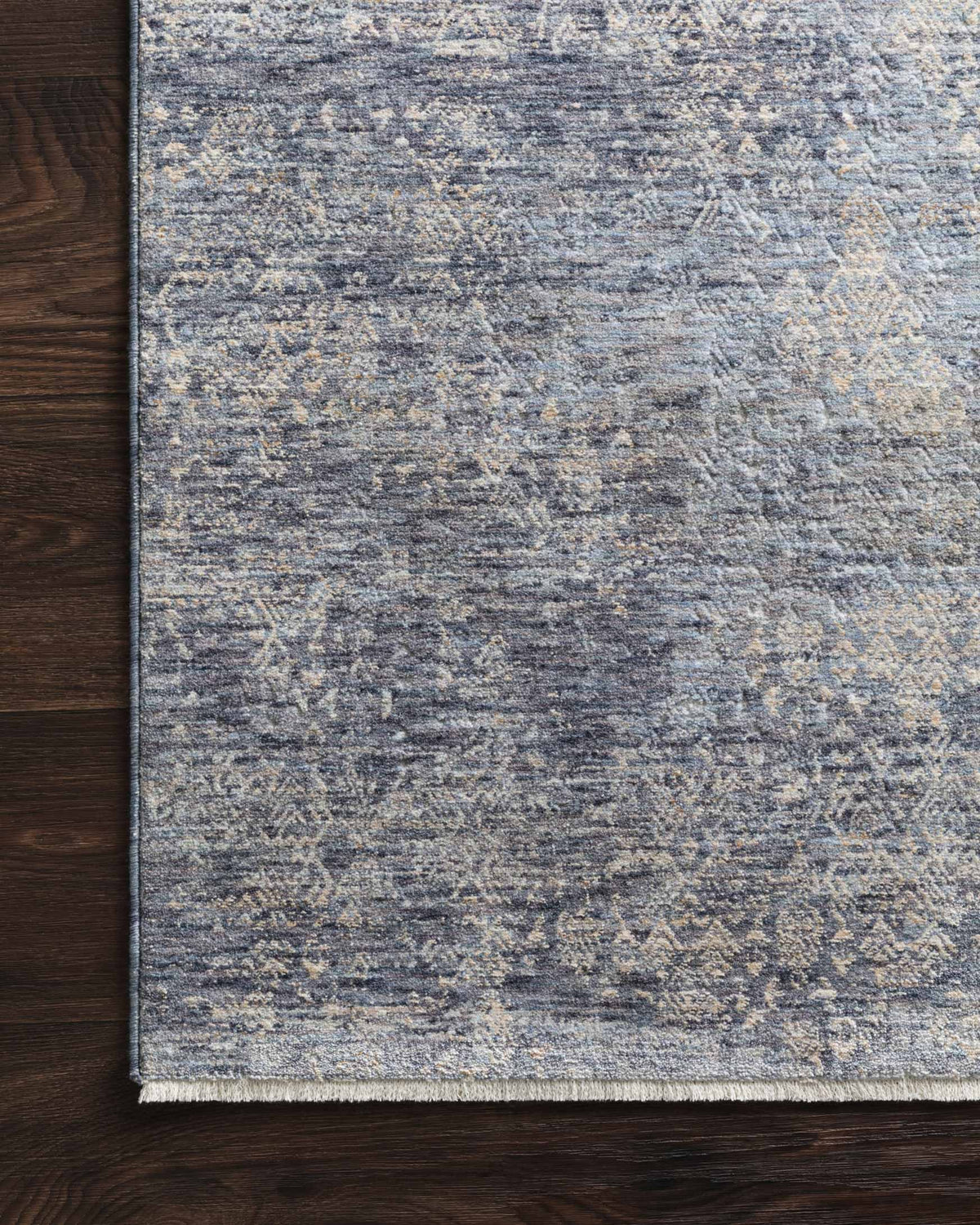 Border edge of dark blue abstract rug with light speckling and low-pile woven texture.