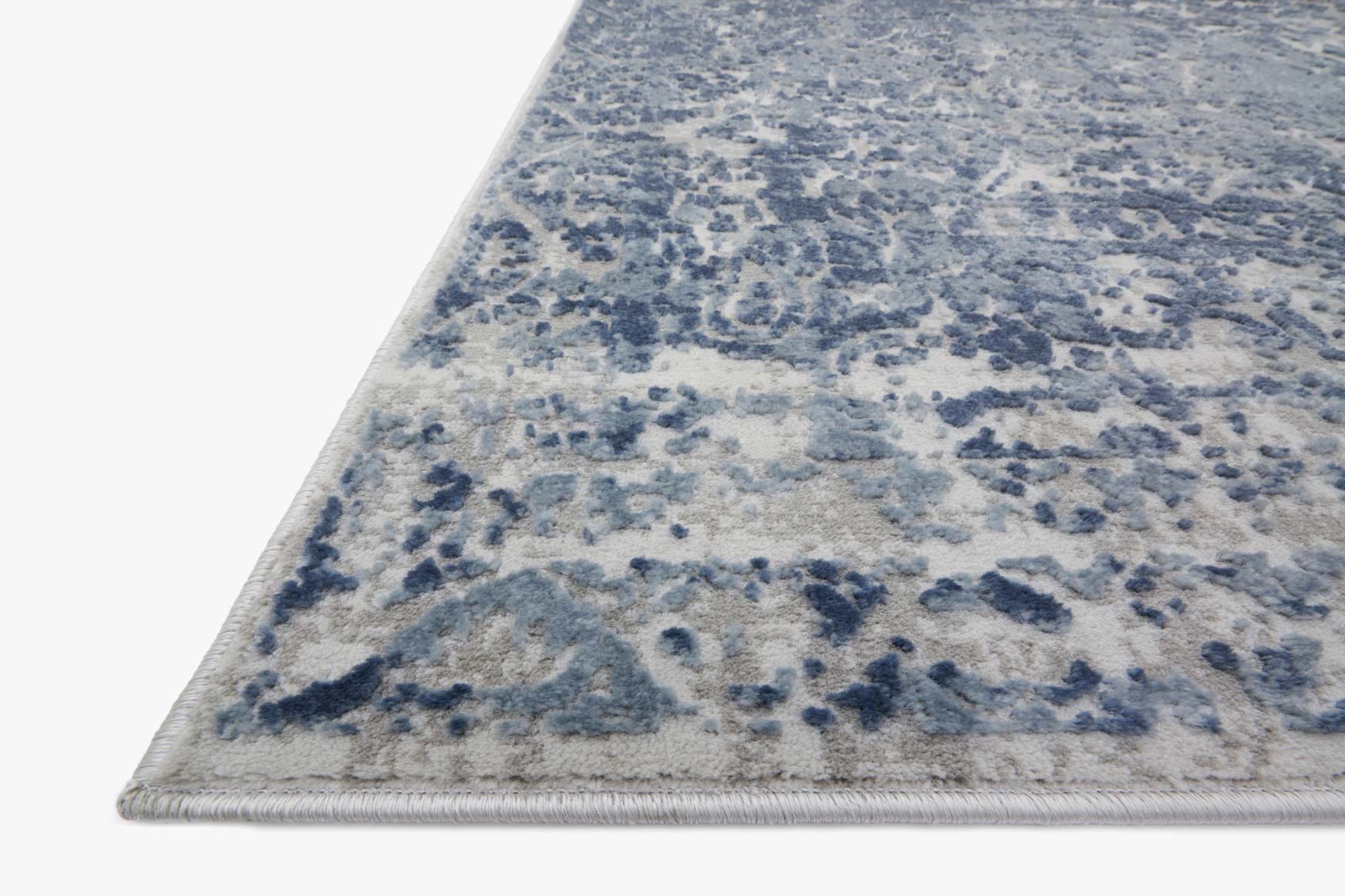 Blue and stone abstract power-loomed rug corner with distressed texture on flat weave