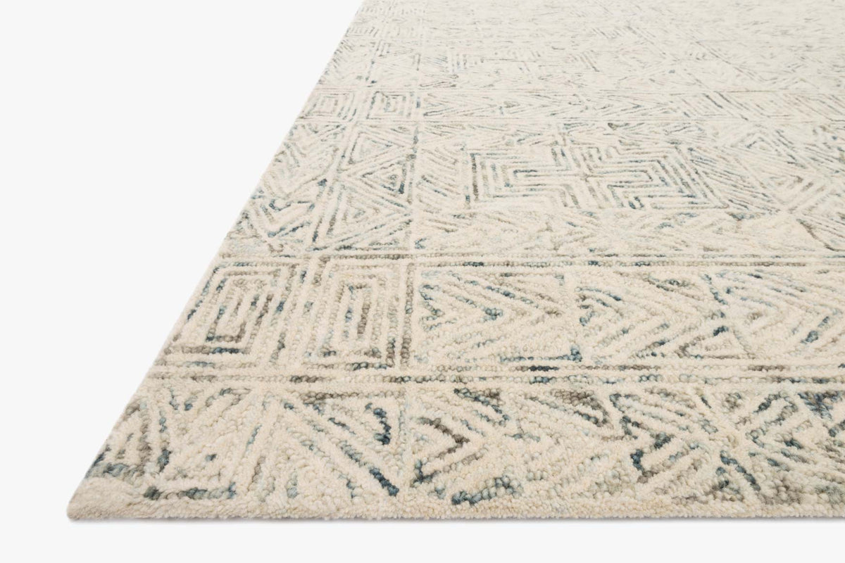 Contemporary hand-tufted rug, light blue geometric motif along angled edge
