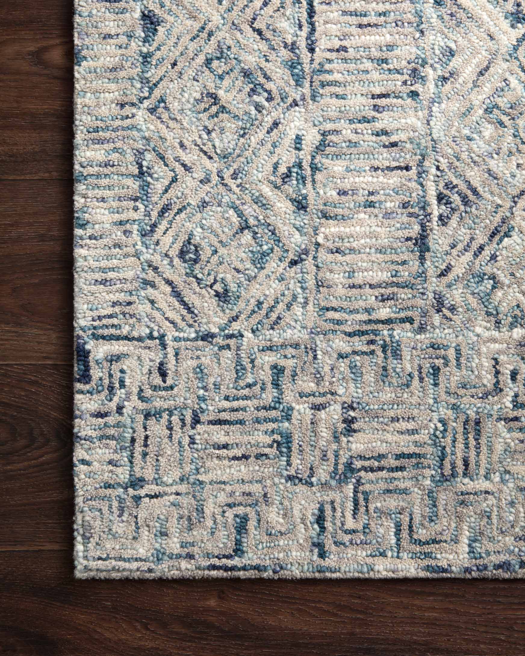 Close-up of ocean blue hand-tufted rug with raised geometric motifs and short textured pile