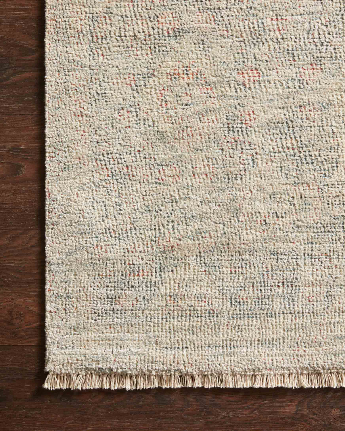 Rectangular ivory rug edge with short fringe and speckled yarn, corner detail