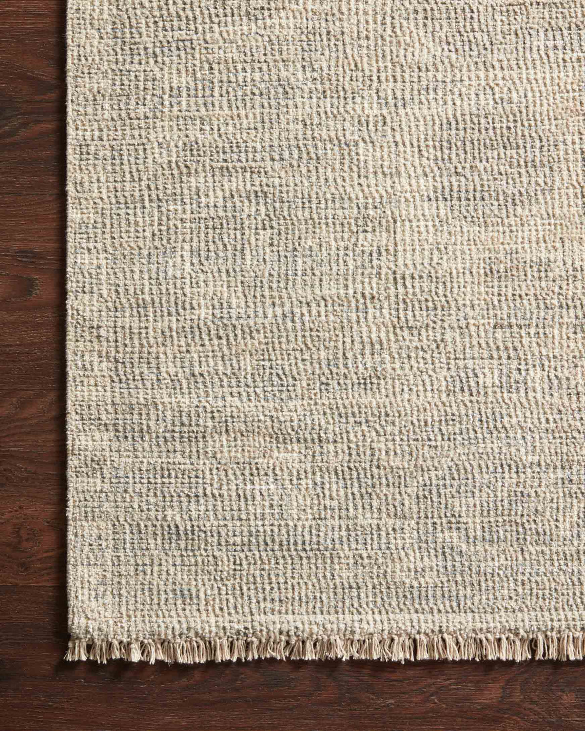 Close-up of ivory and grey handwoven rug texture with fringe trim