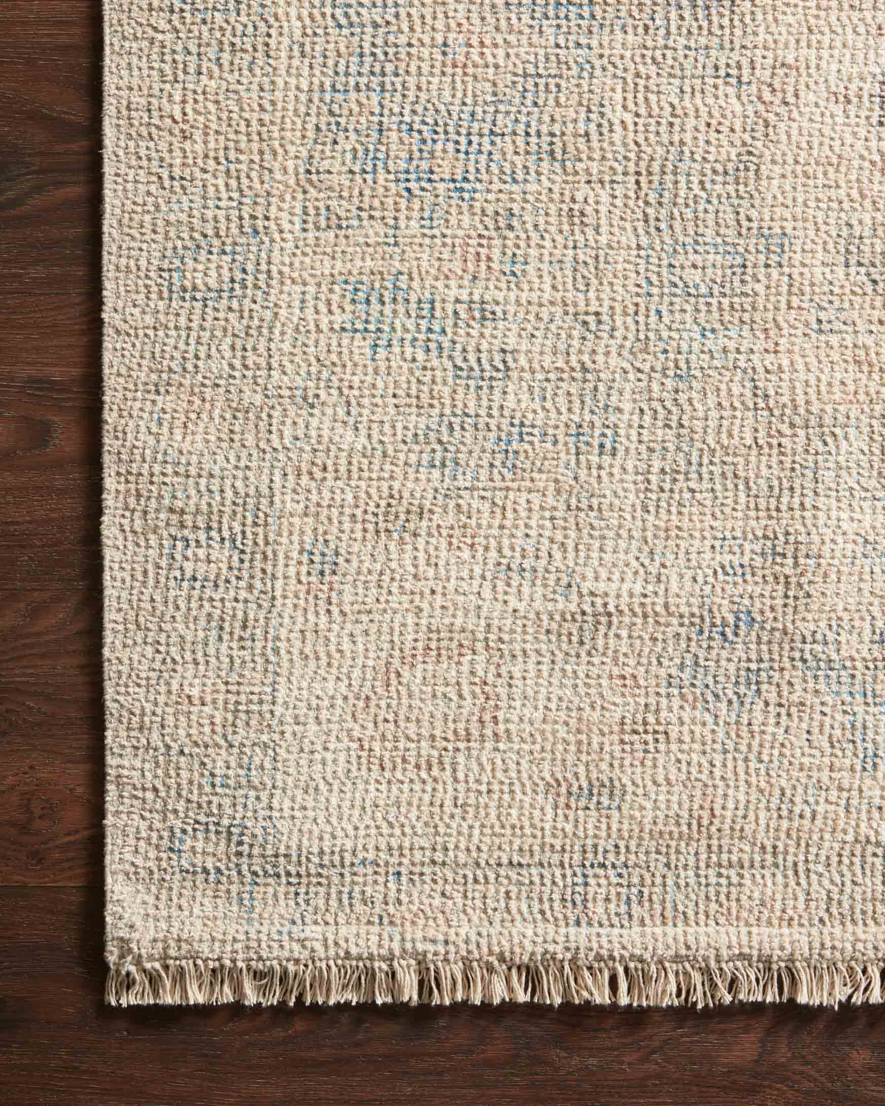 Hand-woven rug close-up with textured weave, light natural fibers, blue accents, fringe.