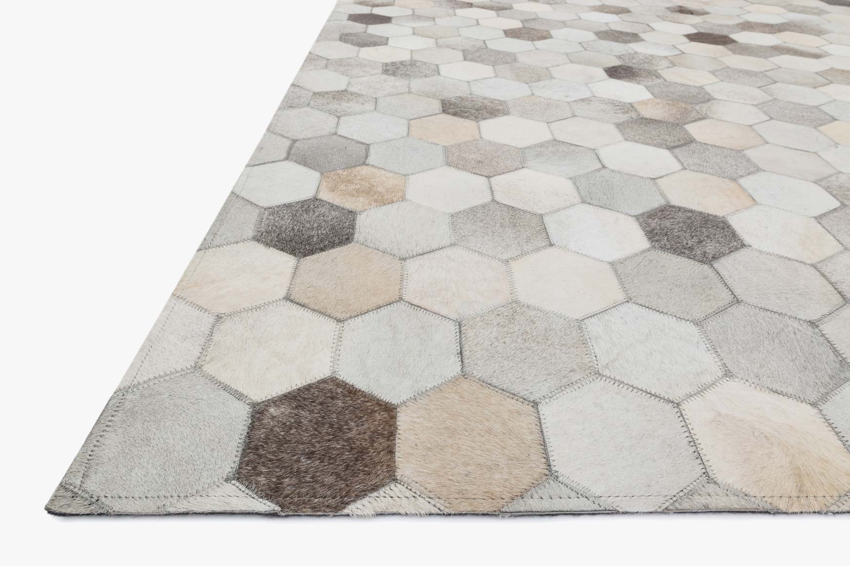 Grey hexagon rug close-up with hand-stitched seams, beige and dark grey cells
