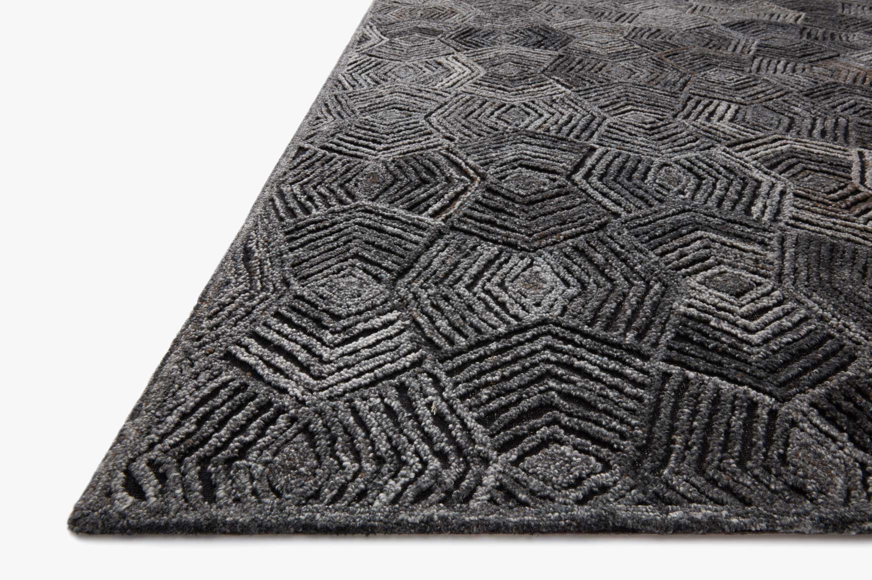 Charcoal geometric hooked rug corner with diamond and zigzag pattern, textured pile
