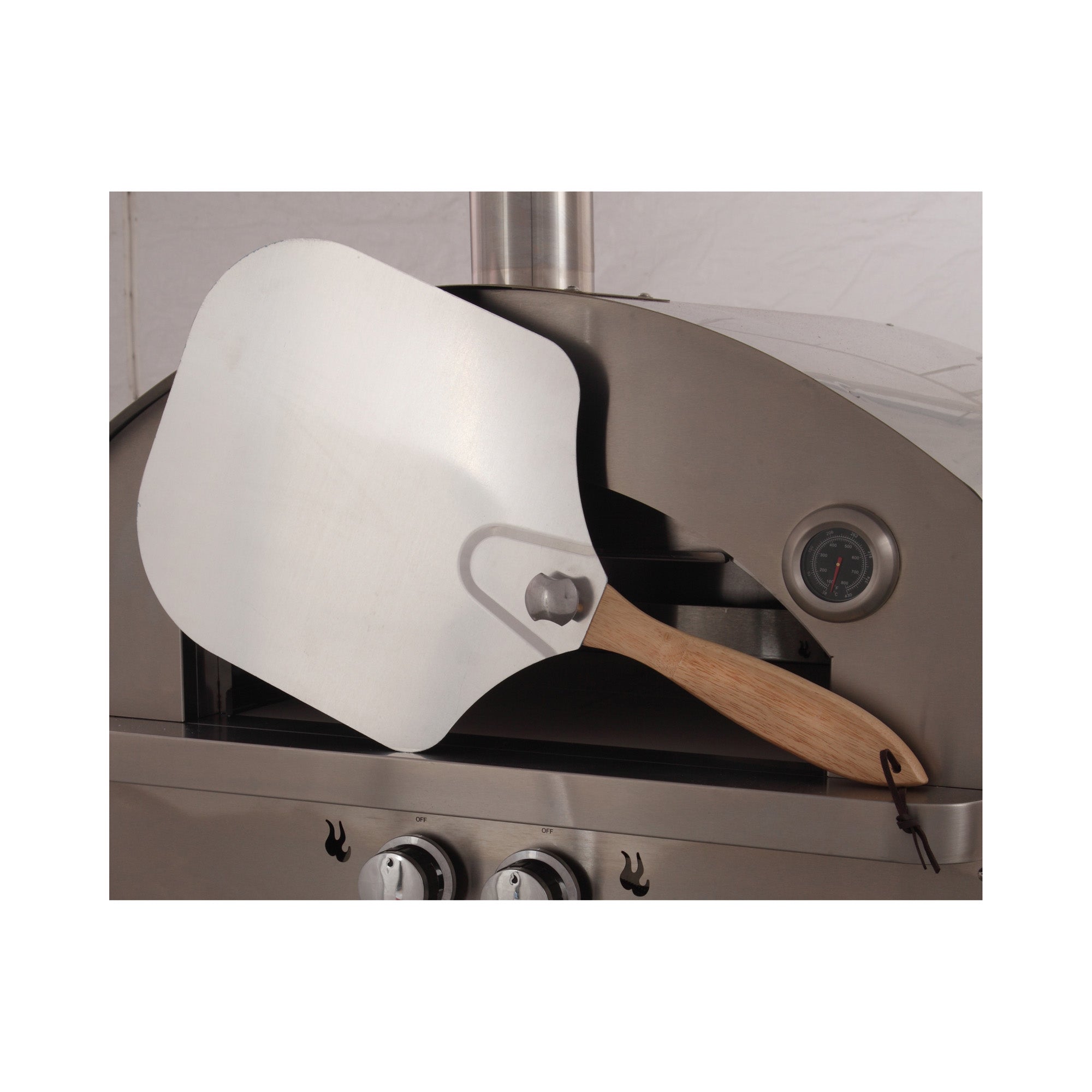 Stainless steel outdoor gas oven with wood pizza peel beside open chamber