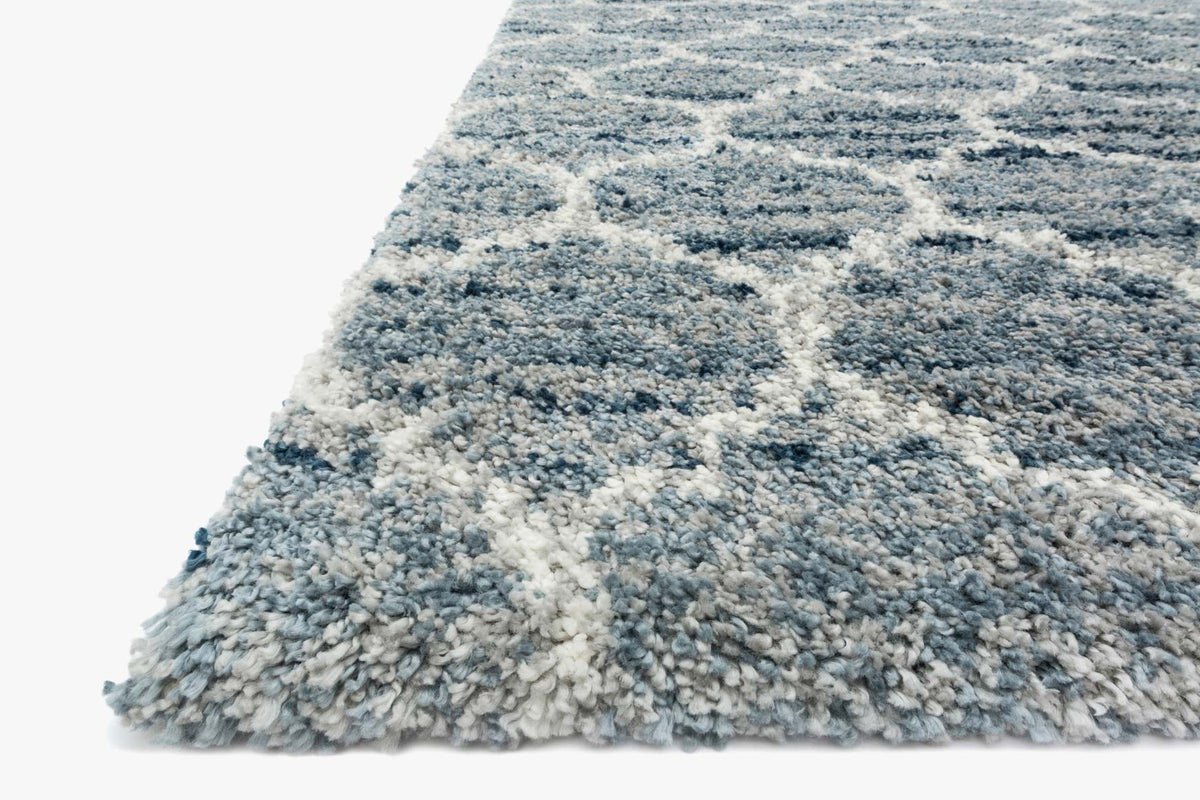 Corner view of shaggy power-loomed rug pile in light blue, gray, and off-white tones