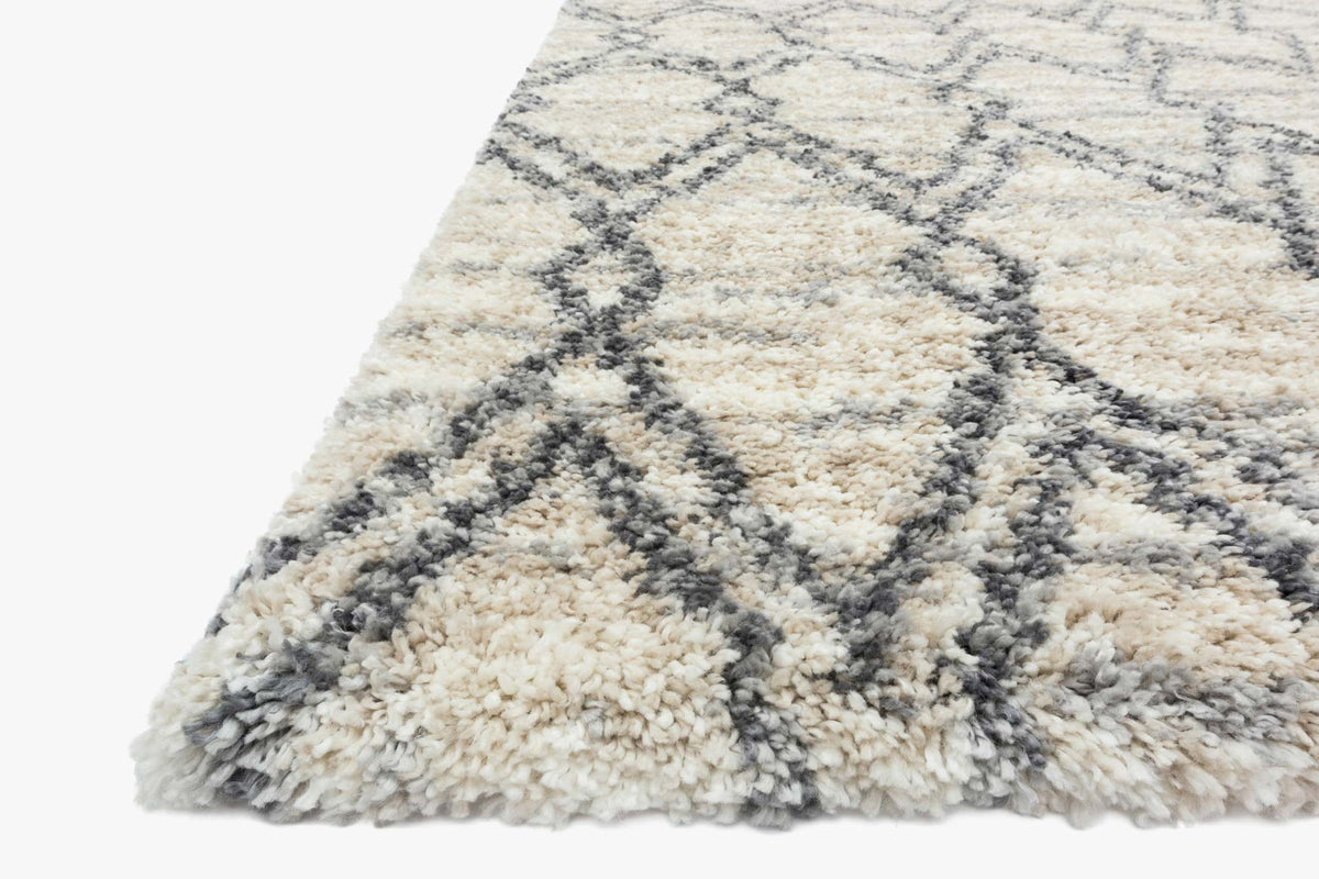 Shag rug corner with cream-and-sand pile and dark graphite geometric pattern