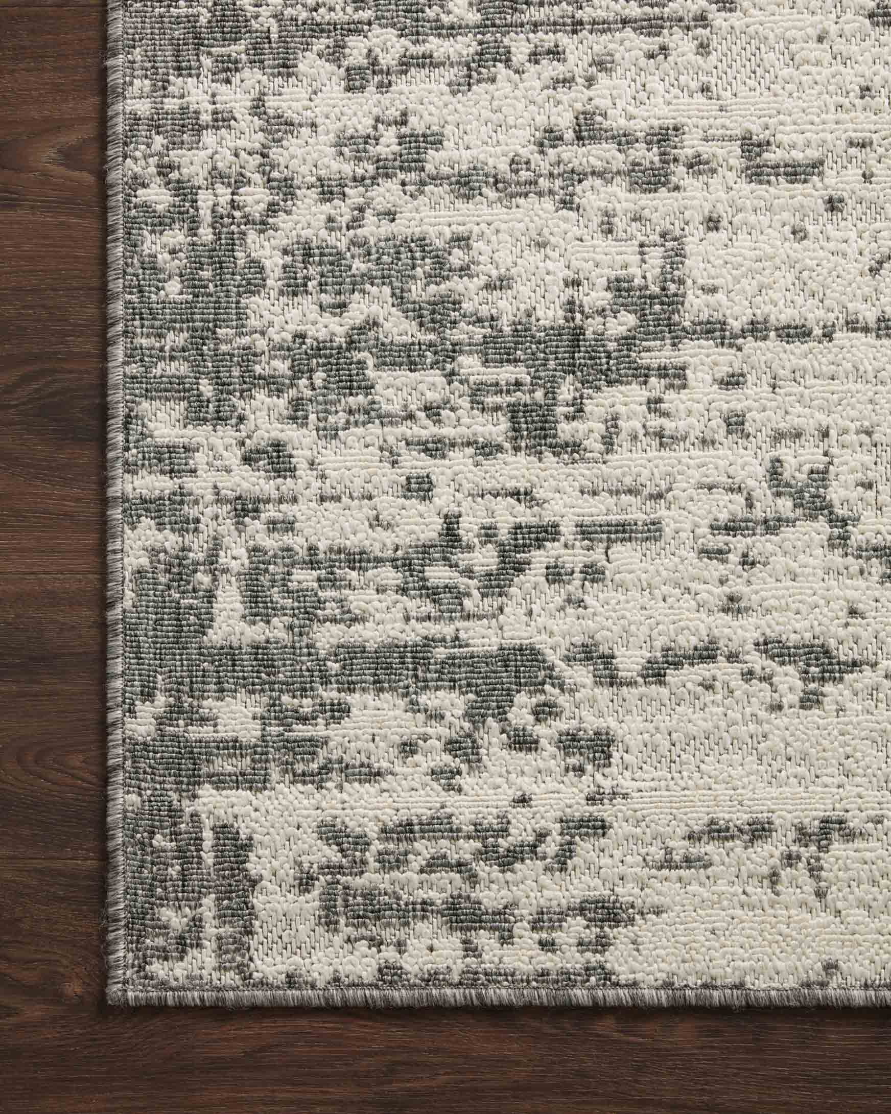 Ivory and grey rug corner on dark wood floor with abstract block pattern