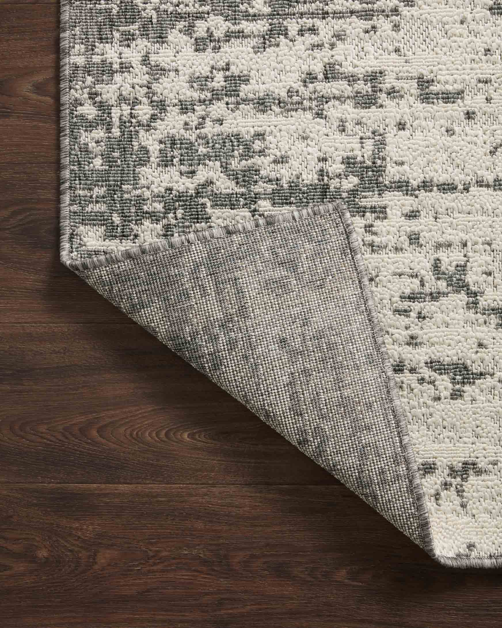 Ivory and grey rug corner showing reverse backing and abstract pattern