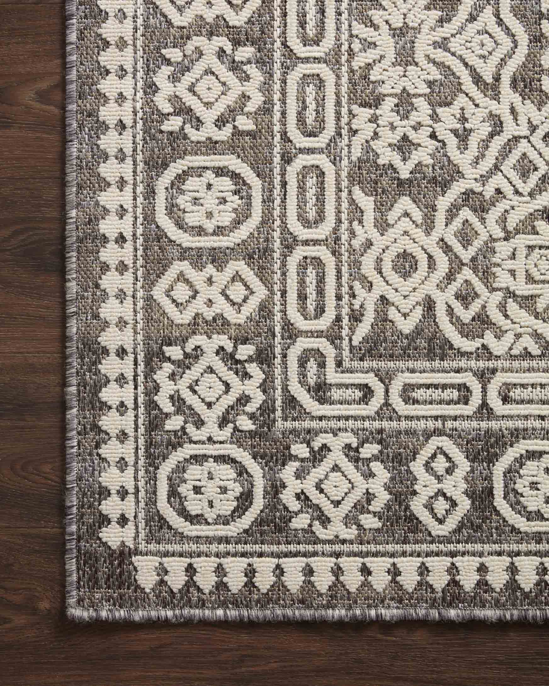 Rug border close-up in pebble gray and ivory featuring medallion and lattice patterns