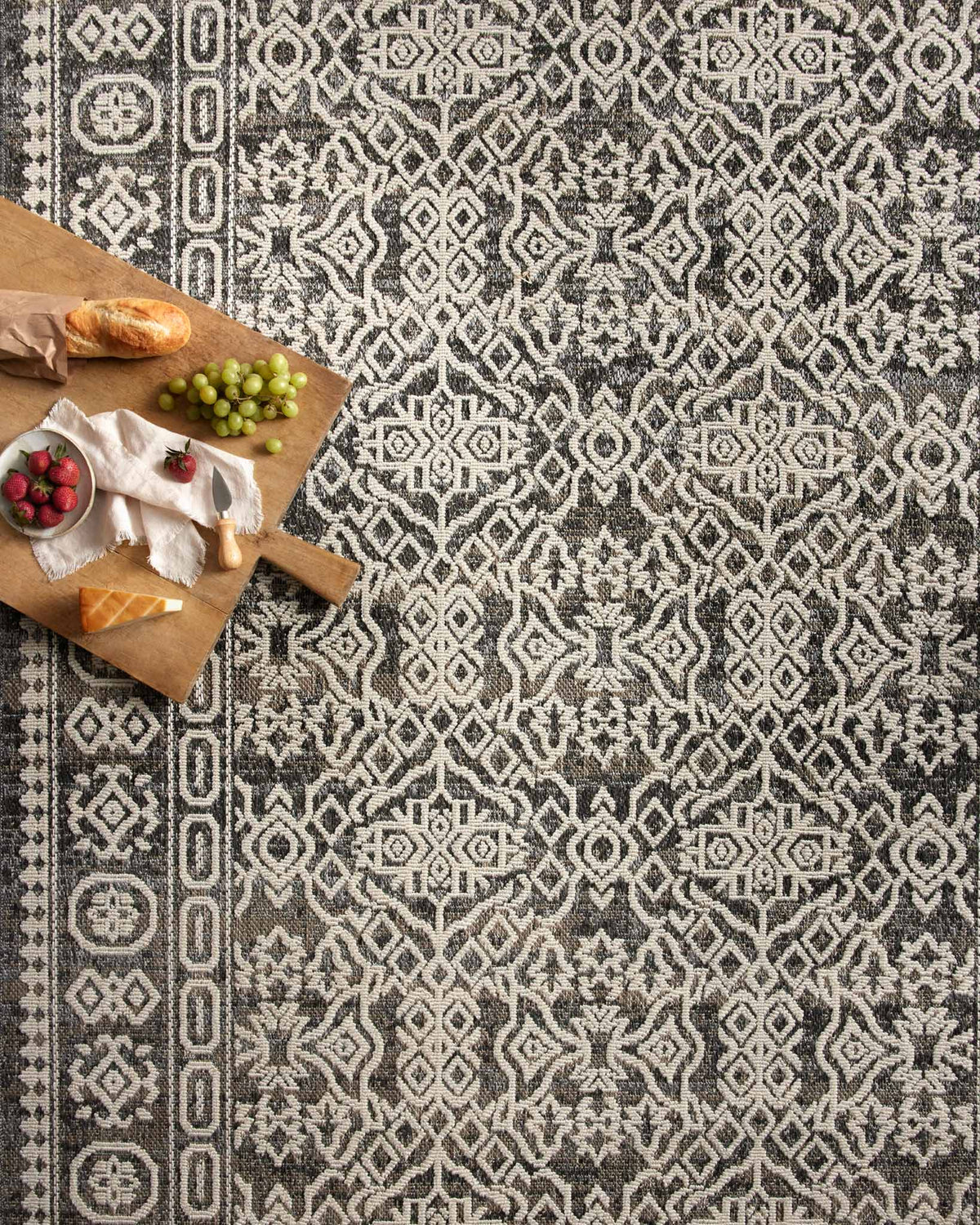 Pebble gray and ivory patterned area rug with repeating diamond and scroll motifs