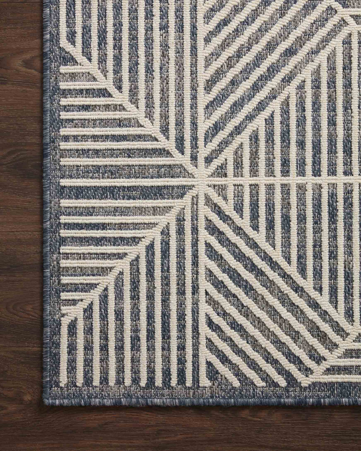 Denim and ivory geometric rug corner with pattern detail on dark wood floor