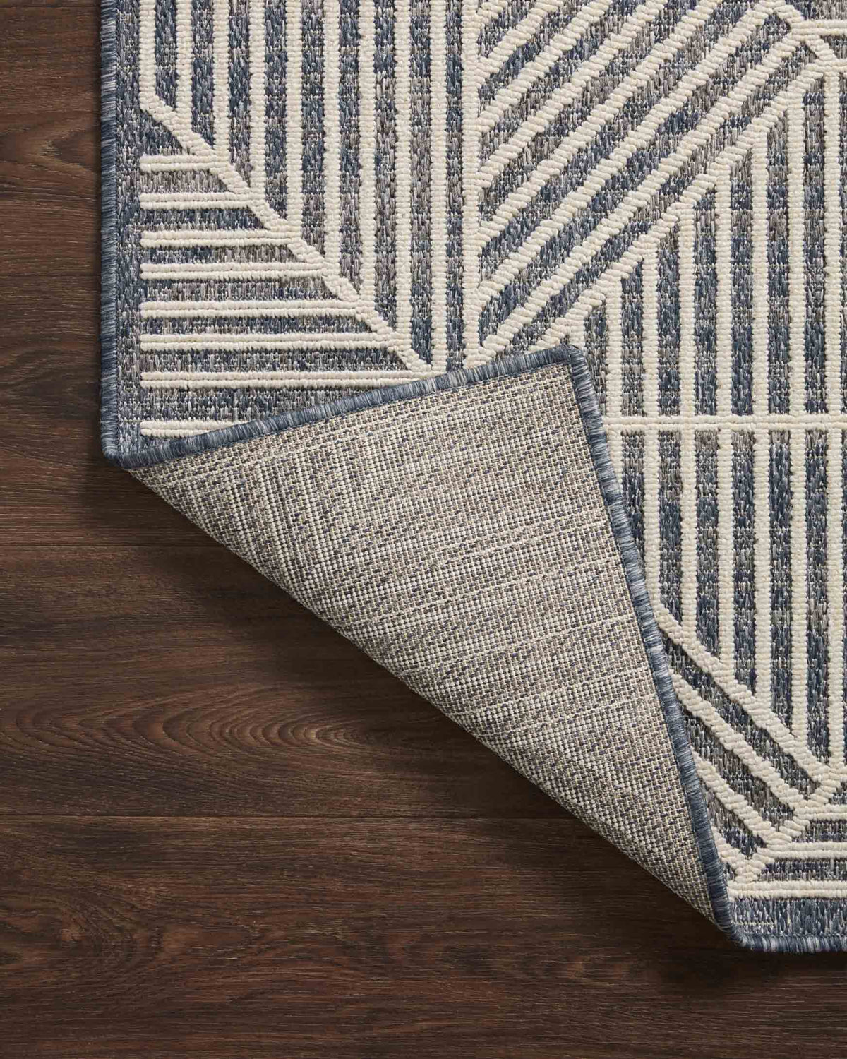 Denim and ivory geometric rug with folded edge showing textured backing