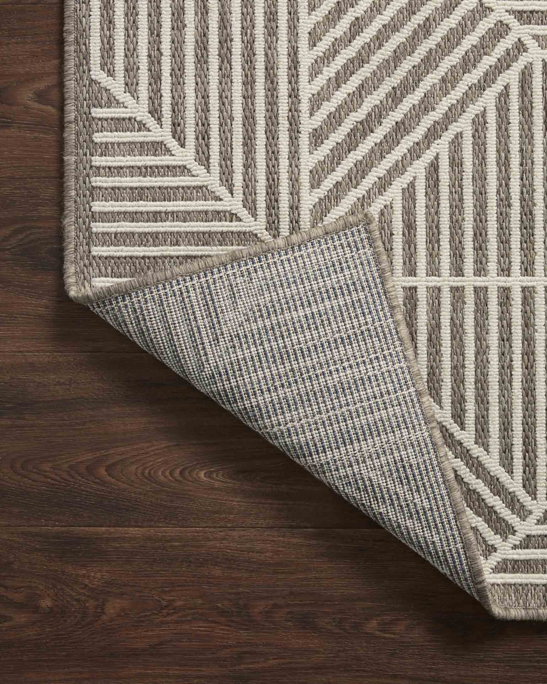 Indoor/outdoor rug edge detail with ivory backing and taupe geometric pattern