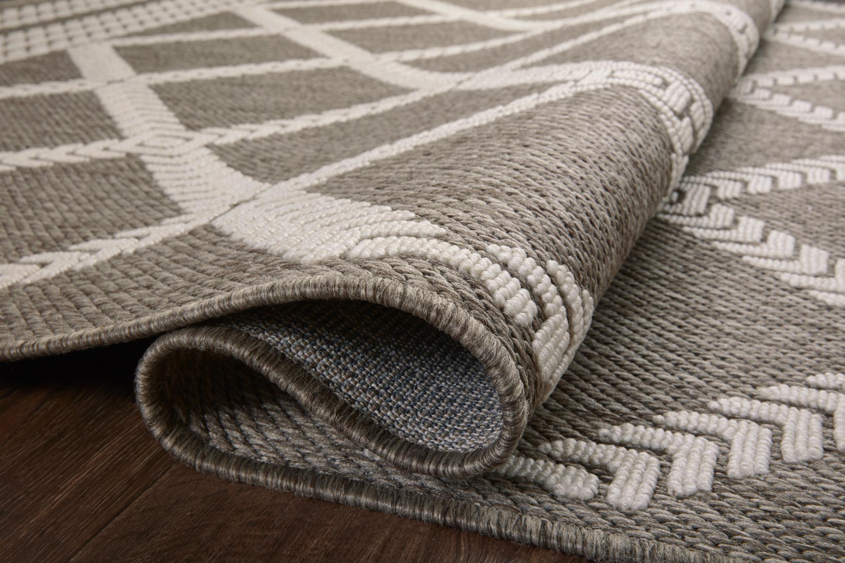 Indoor/outdoor rug close-up showing tightly woven dark gray and ivory design