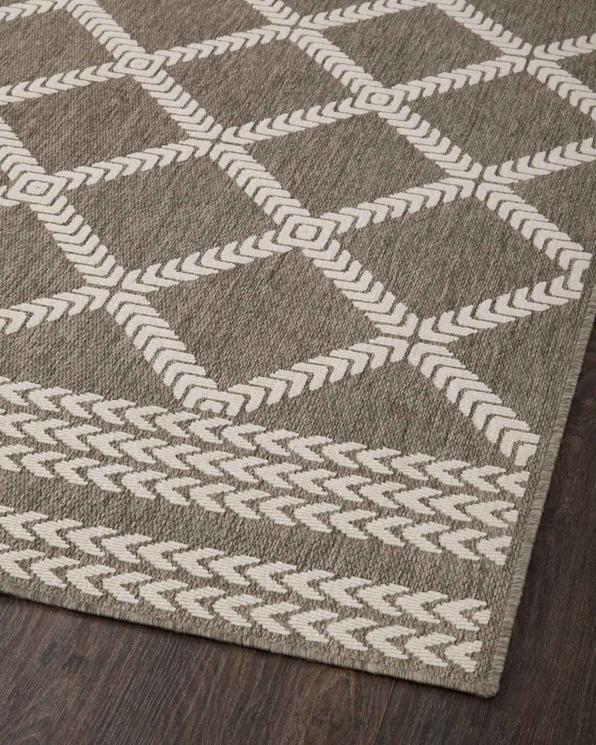 Indoor/outdoor rug featuring repeating dark gray diamond lattice pattern in ivory
