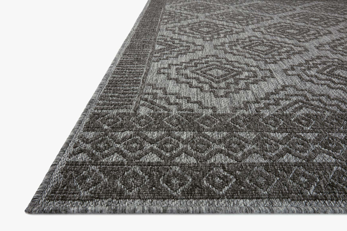 Grey and charcoal rug corner with dense geometric pattern and tight woven border.