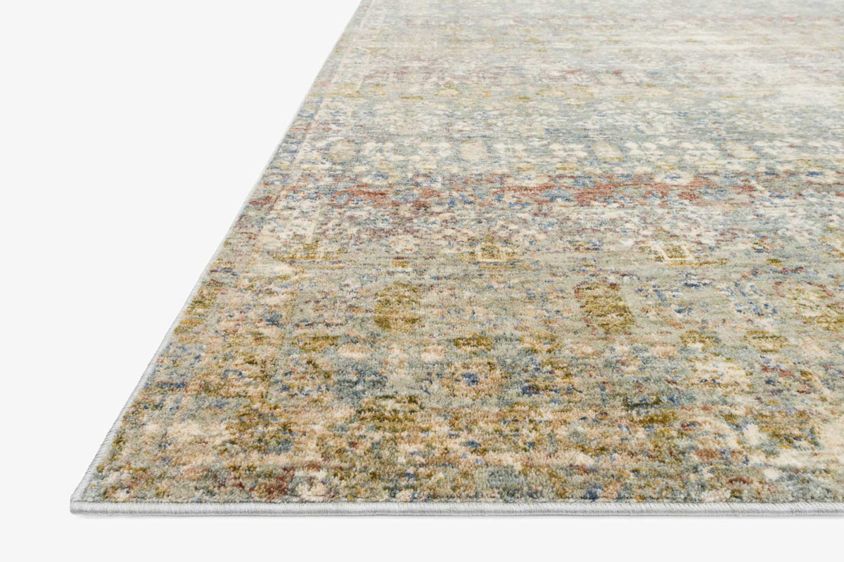 Corner view of traditional power loom rug with muted grey, gold, and rust speckled pattern