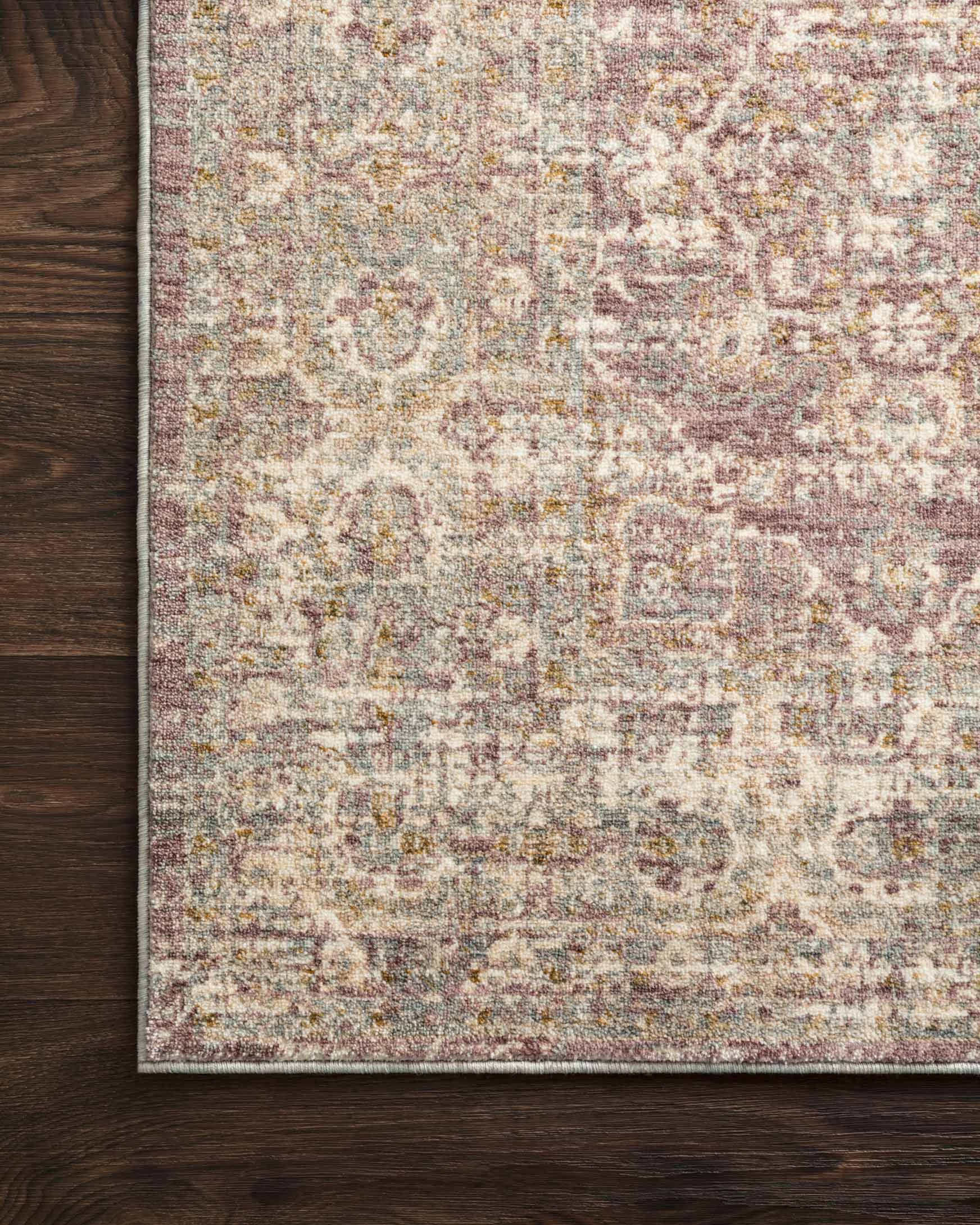 Traditional power-loomed rug edge detail with distressed lilac, beige, and gray pattern.