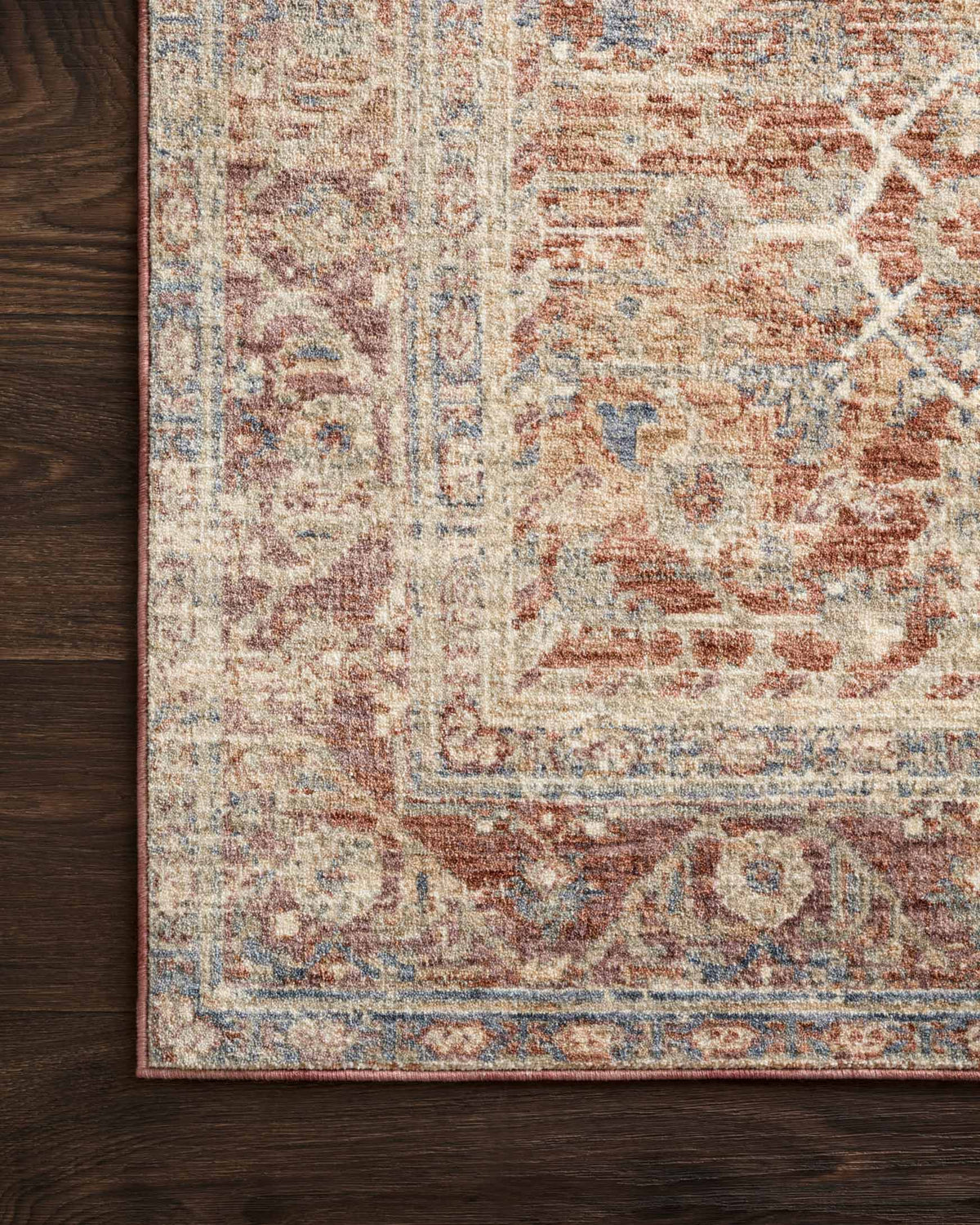 Traditional power loomed rug close-up with ornate distressed motifs in terracotta, beige, and teal