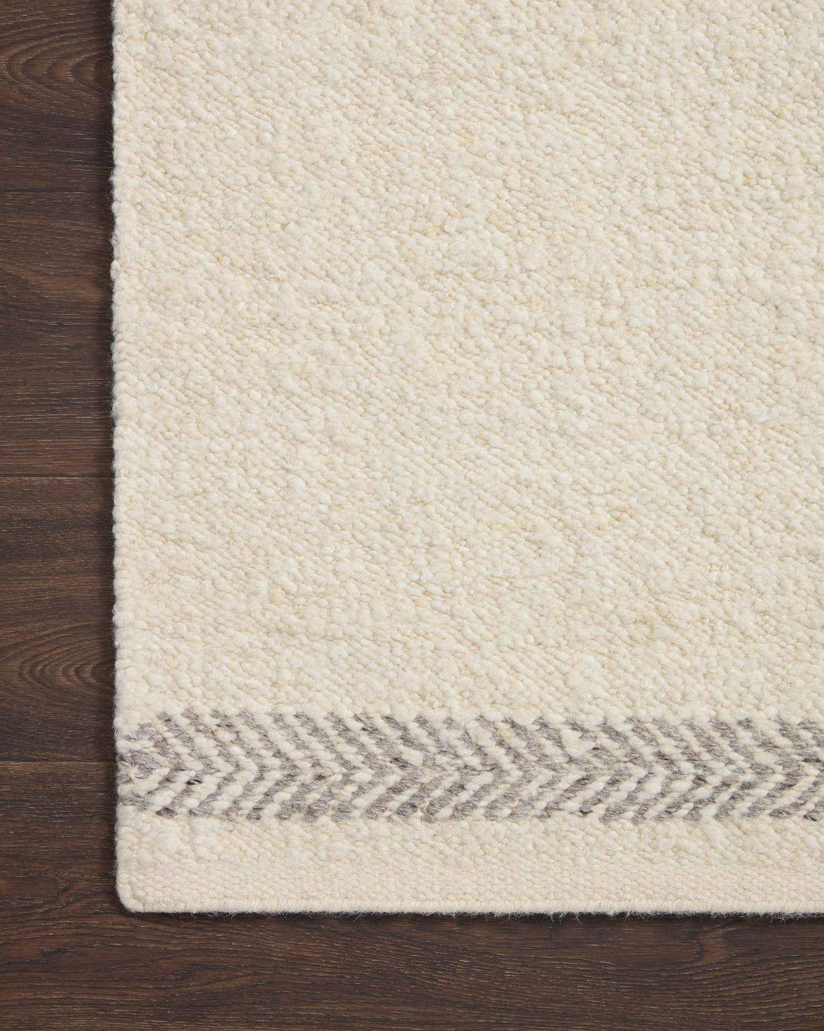 Ivory textured rug with silver pattern stripe along the edge