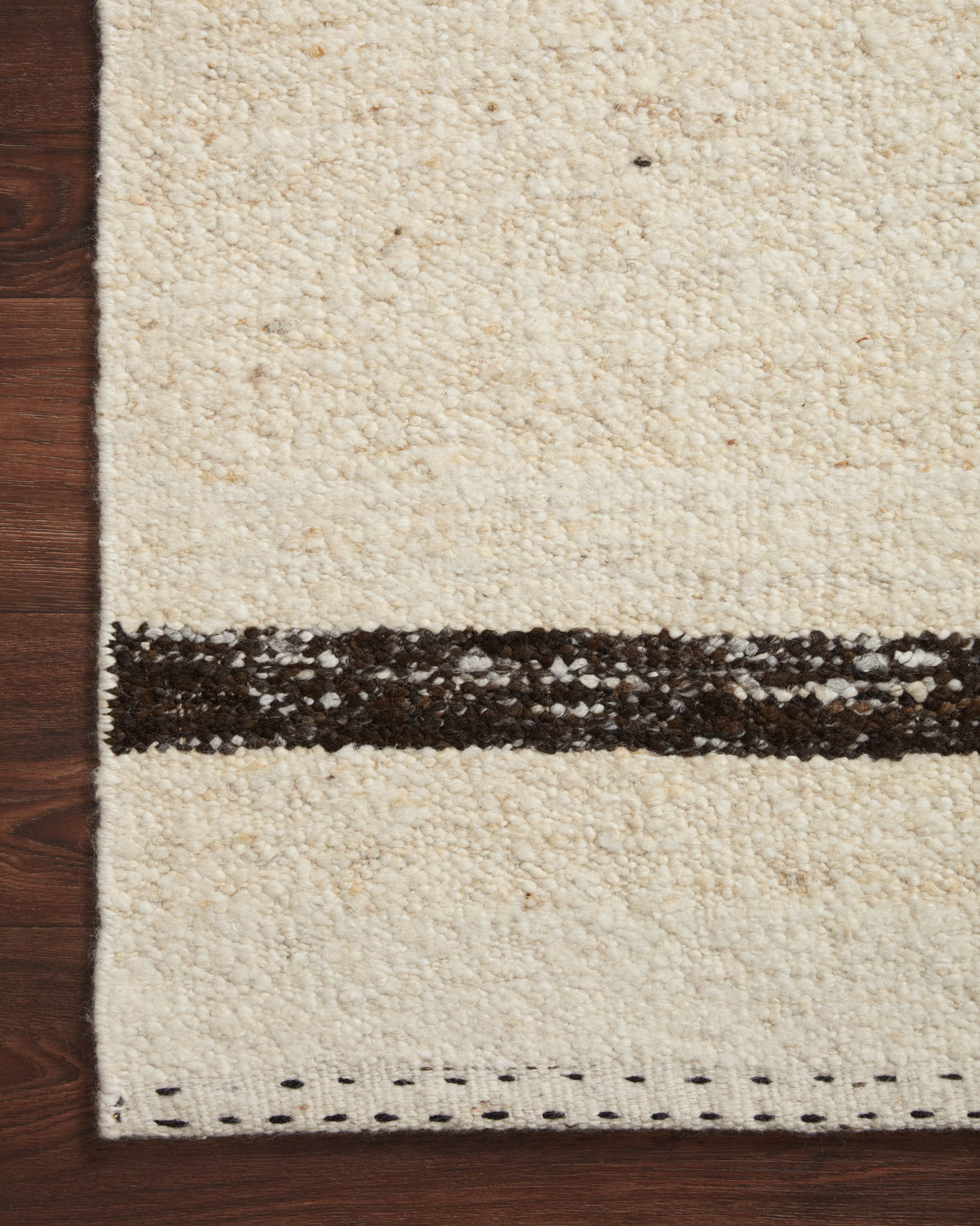 Natural rug close-up with dark-brown border stripe and visible woven texture
