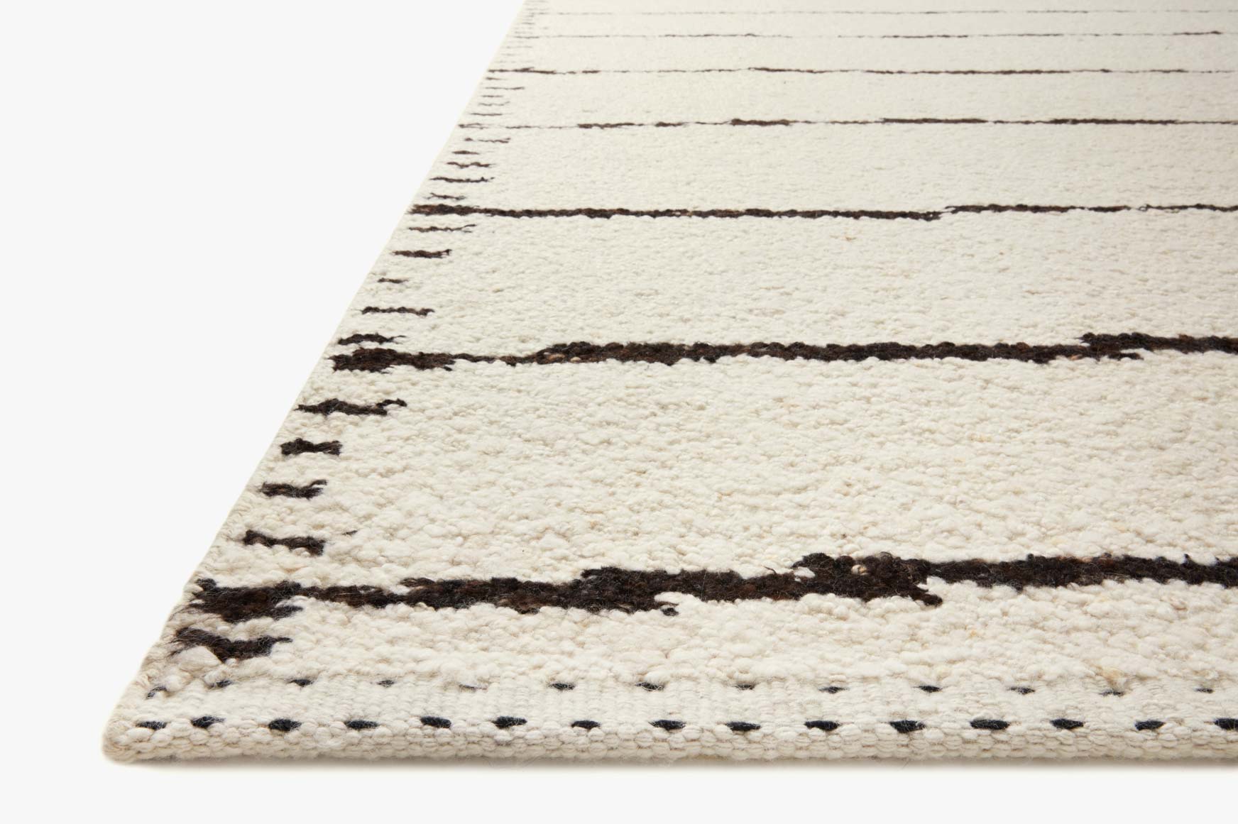 Ivory rug corner with horizontal black bands and short fringe along the edge